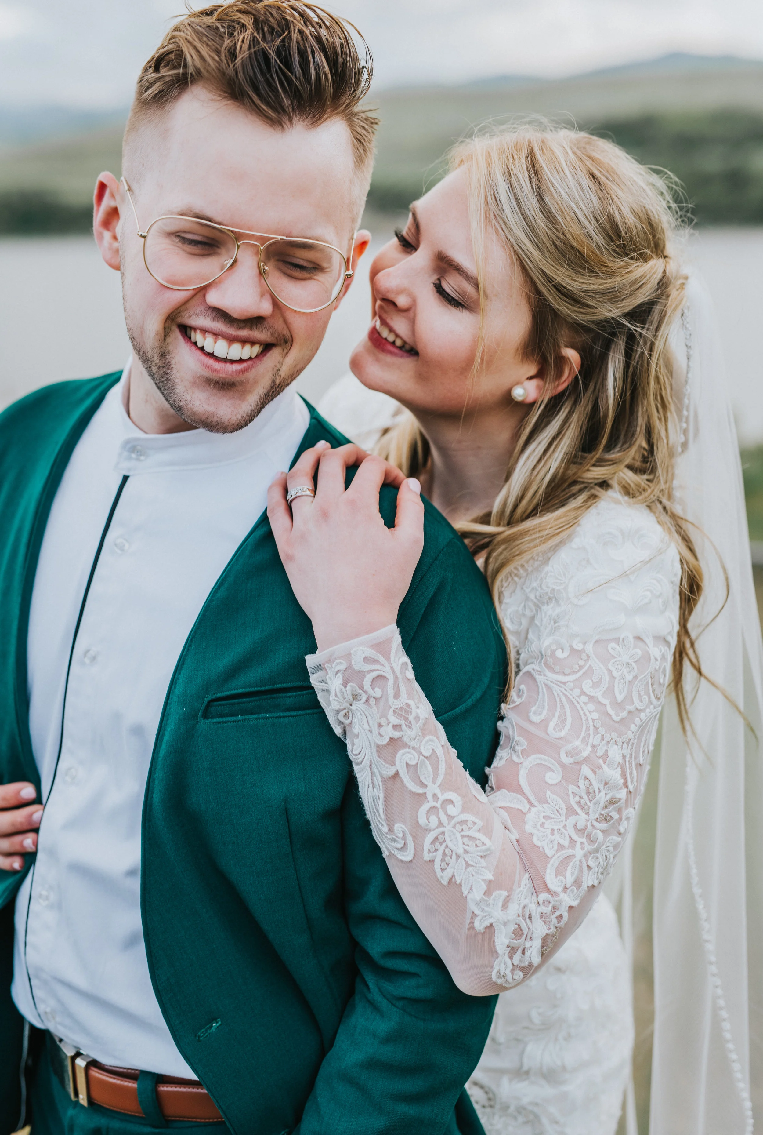  laughing hugging playful bridals formal wedding photos hyrum reservoir northern utah wedding photographer retro glasses green wedding suit modest lace wedding dress tussled hair wedding rings #cachevalleyutah #hyrumutah #northernutahphotographer #br
