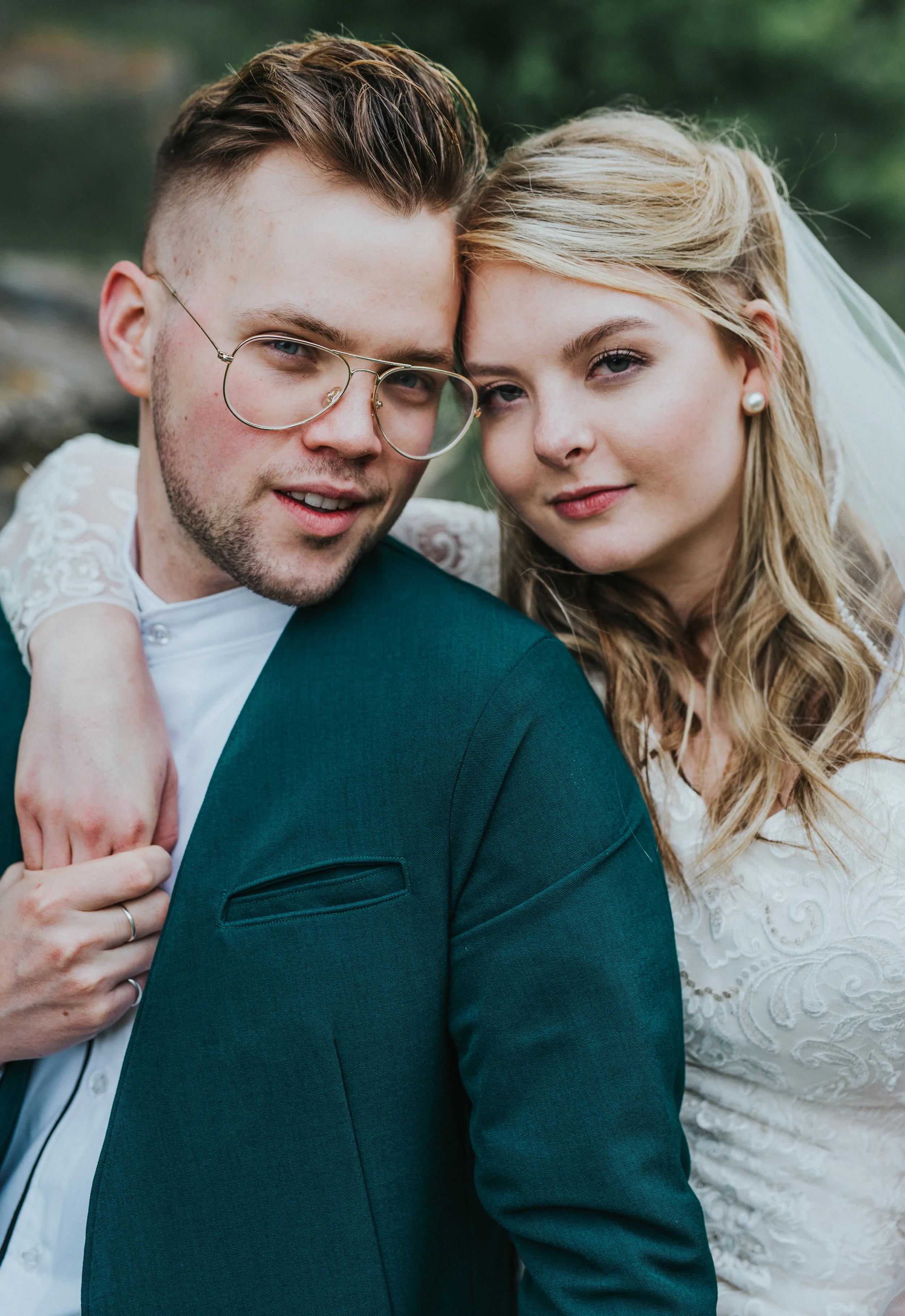  bridal portraits emerald green suit jacket retro glasses lace modest wedding dress loose curls hair inspiration sitting hugging northern utah wedding photographer black smith fork canyon hyrum reservoir utah #cachevalleyutah #hyrumutah #northernutah