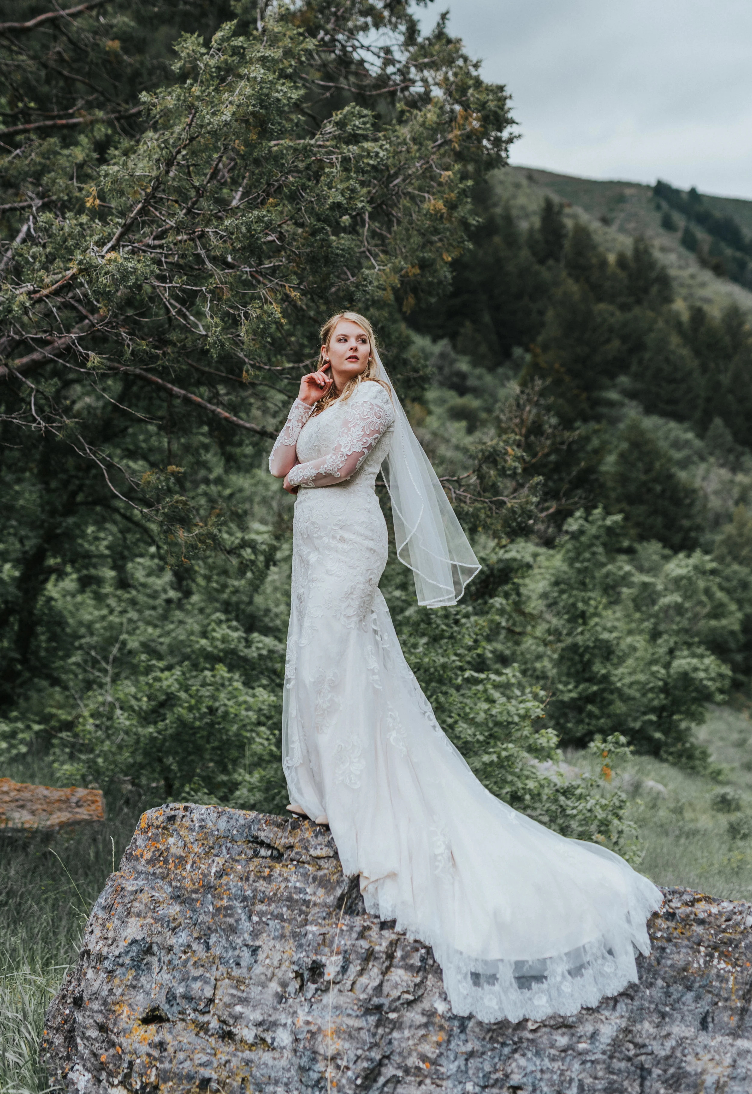  long white wedding train lace modest wedding dress hyrum reservoir logan utah wedding photographer bridals bride poses lush green trees posed on rocks #cachevalleyutah #hyrumutah #northernutahphotographer #bridals #hyrumreservoir #blacksmithforkcany