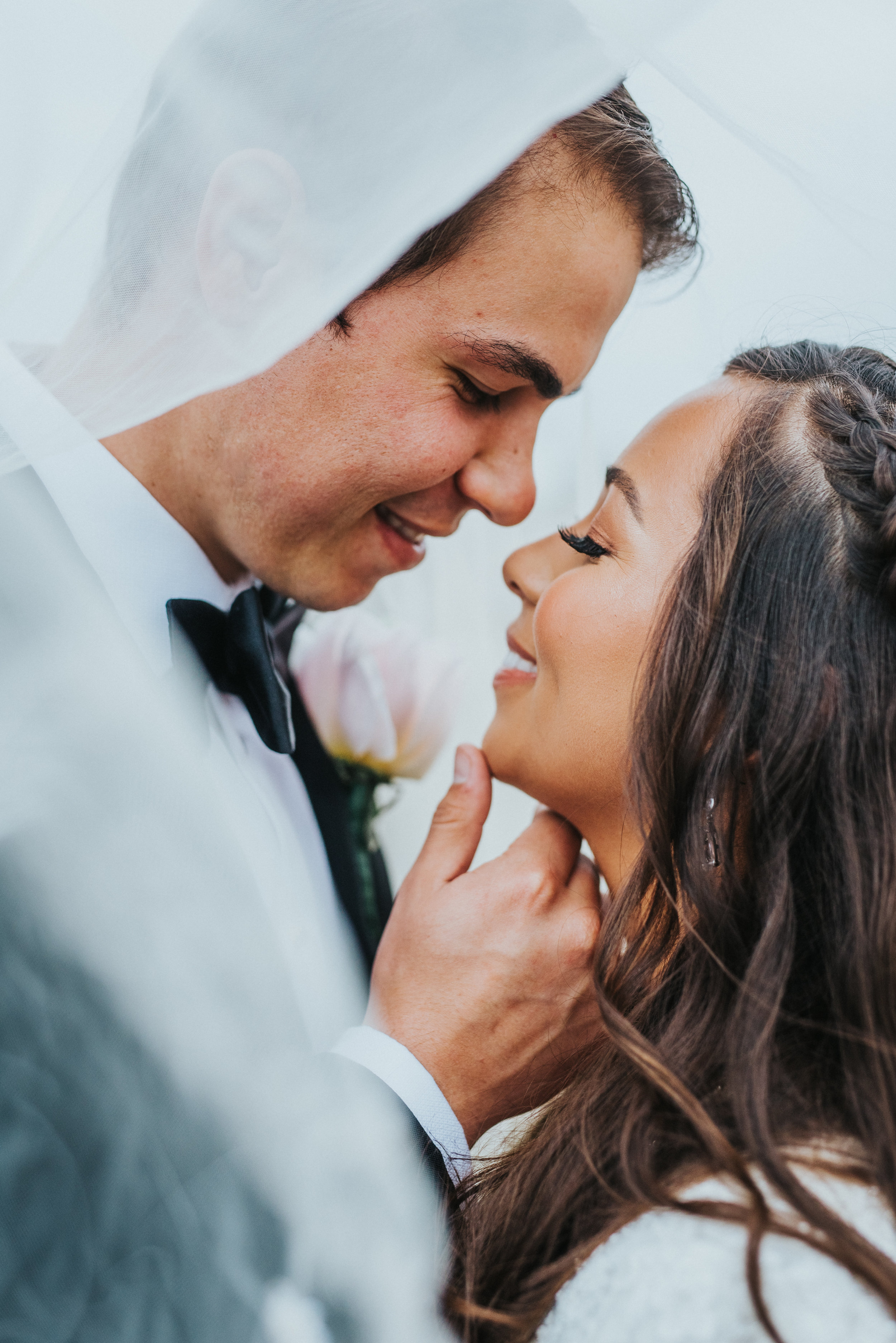  billowy under the wedding veil romantic photo smiling happy tipping chin gray wedding suit pink peony boutonniere san diego california wedding photographer formal bridals #lajollacaliforniaweddingphotographer #sandiegotemple #windanseabeachcaliforni