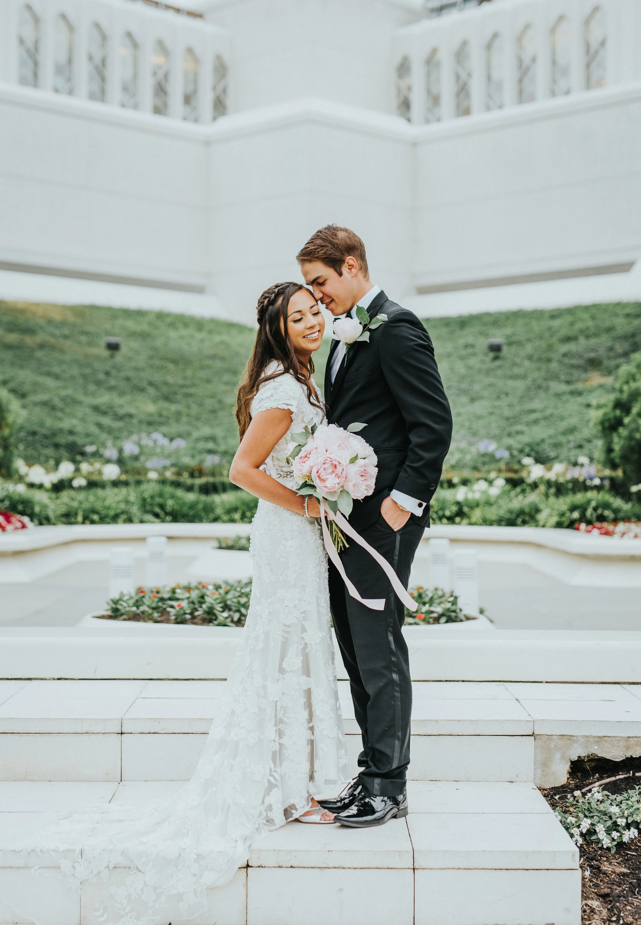  san diego lds temple windy bouquet ribbon beaded lace modest wedding dress cap sleeve hugging pink peopny bouquet boutonnière hand in pocket groom san diego wedding photography northern utah wedding photographer #lajollacaliforniaweddingphotographer