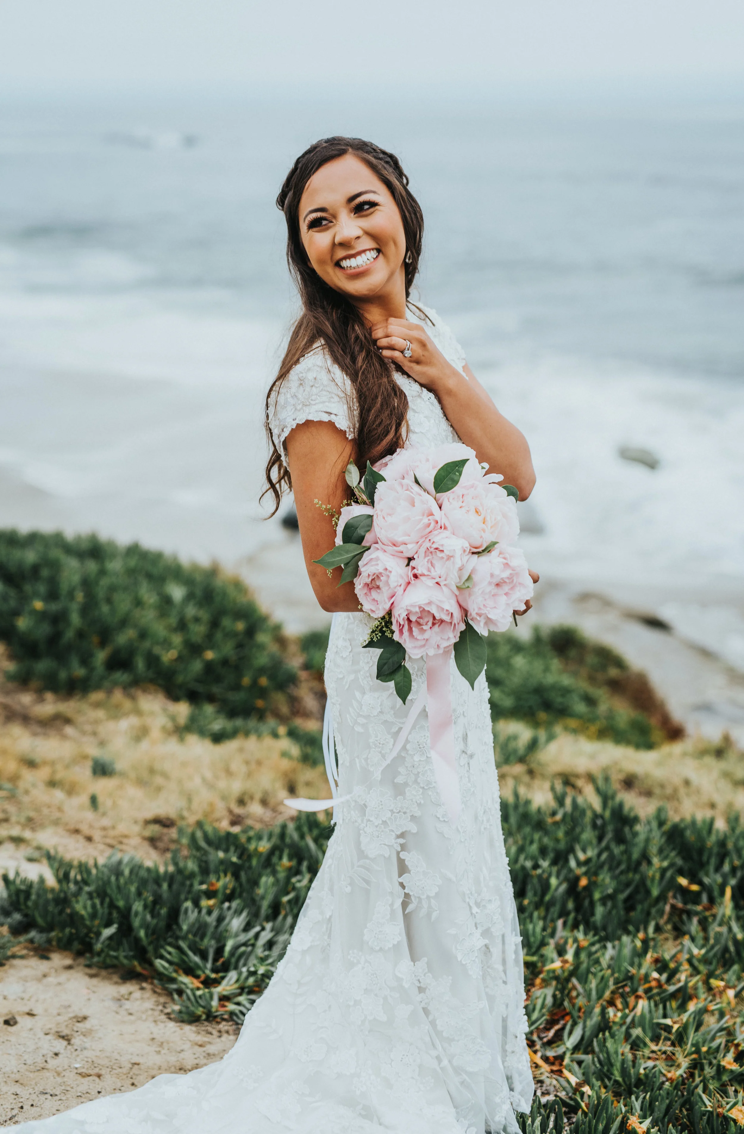  pink peony wedding bouquet window bouquet ribbons cap sleeved lace wedding dress modest loose wedding curls braided hair inspiration windansea beach la jolla california northern utah wedding photographer #lajollacaliforniaweddingphotographer #sandie