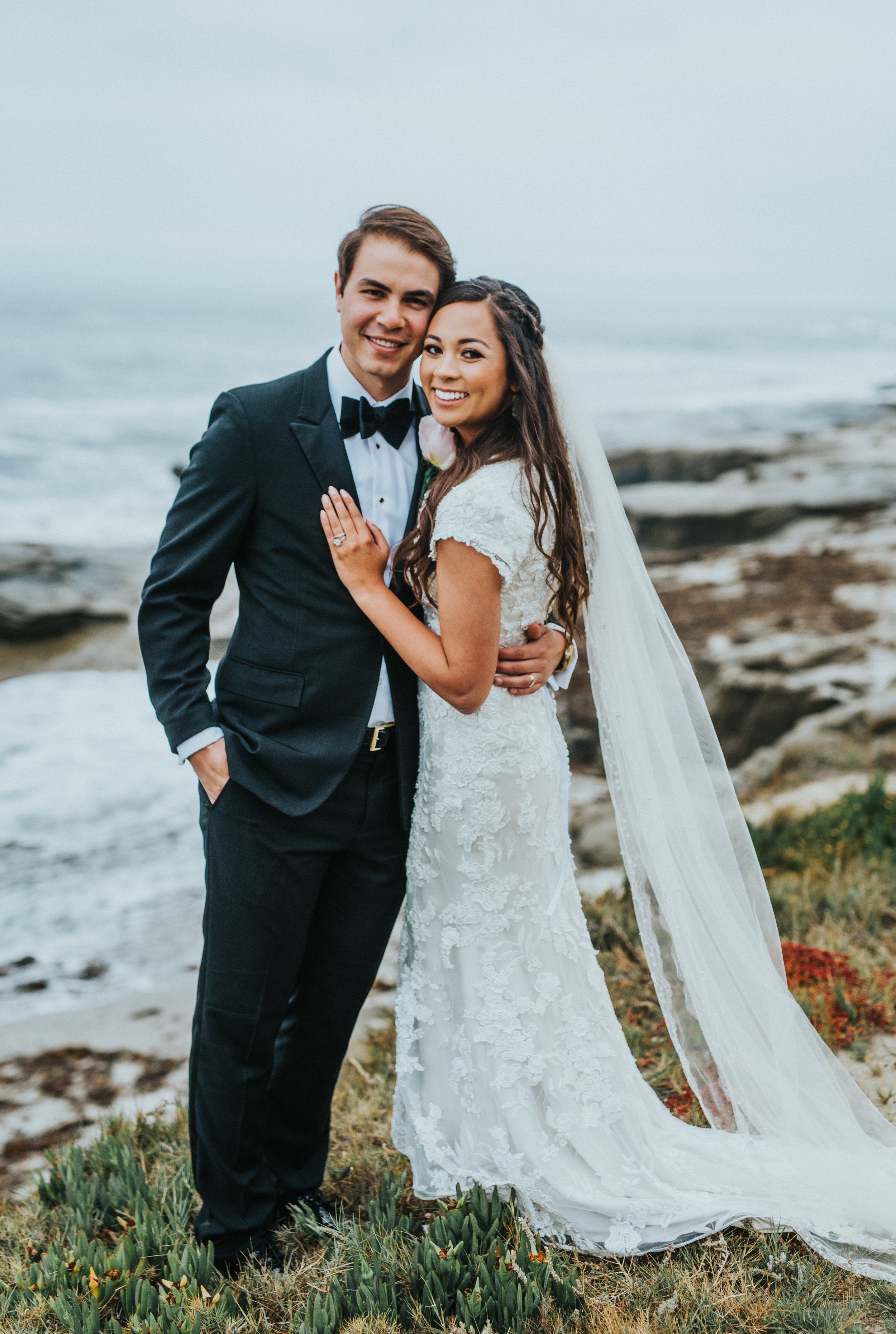  hand on chest hugging smiling celebrating long bridal veil loose bridal curls hair inspiration beaded wedding dress windansea beach la jolla california san diego wedding photographer #lajollacaliforniaweddingphotographer #sandiegotemple #windanseabe