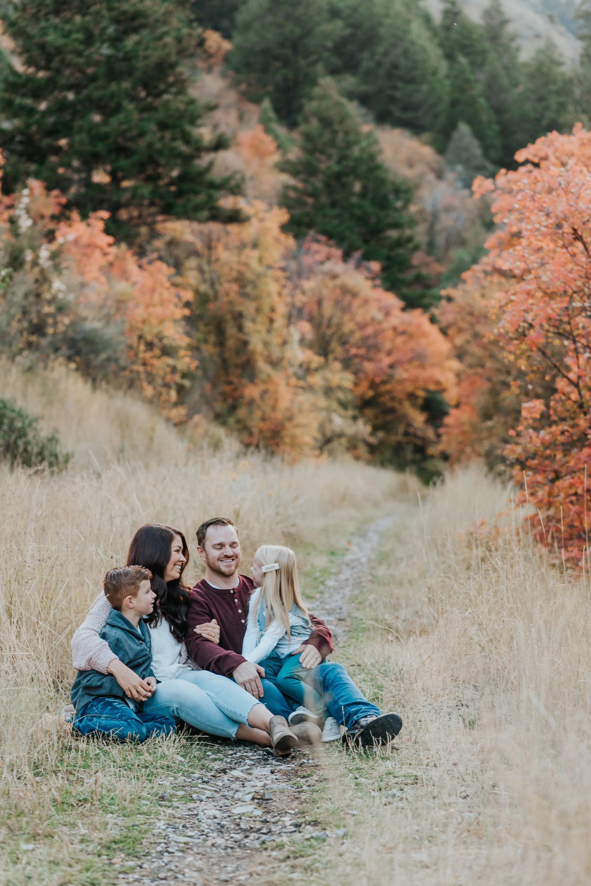  family photo session pictures in the mountains cache valley Logan Utah fall colors family sitting together family of four posing ideas family posing precious moments family time happy day laughing family family sitting in a field fall family photos 