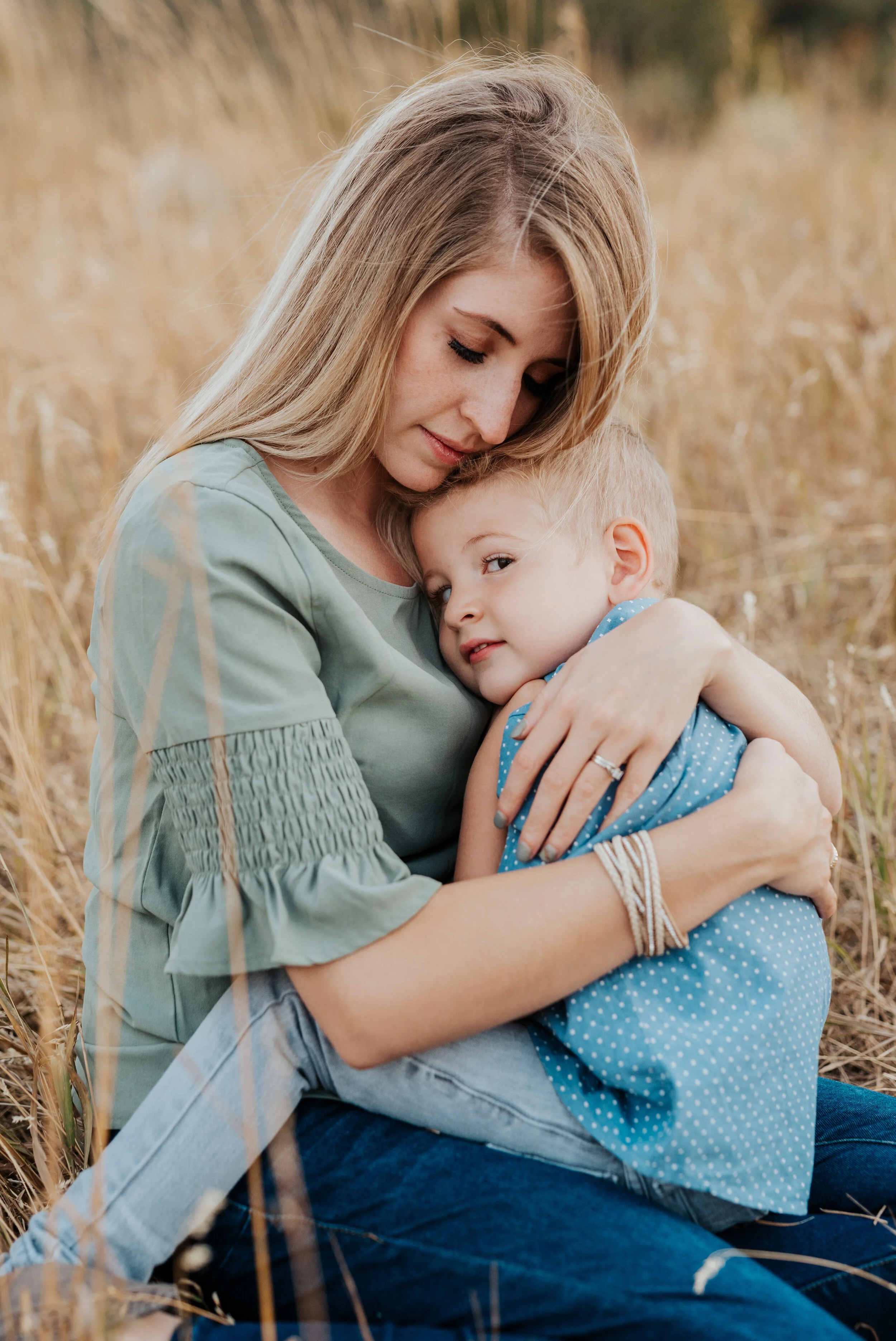  Mom giving her sweet little boy a big cuddle while they sit in the golden grass. cache valley photographers in northern utah professional photographers in utah family pregnancy pose inspiration casual outfit styles sweet parent and children poses ba