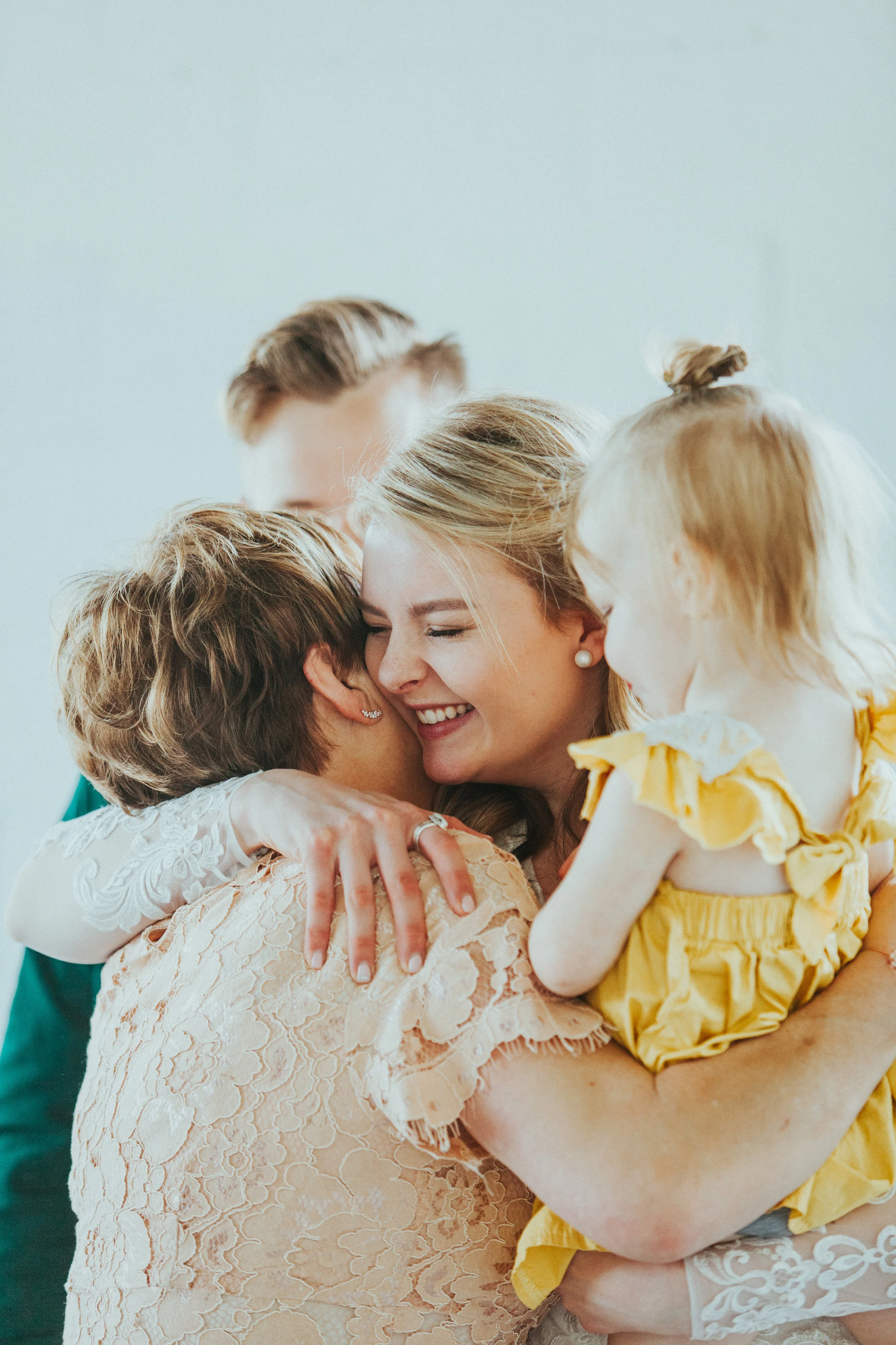  white studio minimalist wedding ceremony just married hugging bride mother of the groom embracing holding toddler family happy professional cache valley wedding photographer #StationStudio #WeddingCeremony #Loganutahtemple #FreckleFarm #cachevalleyu