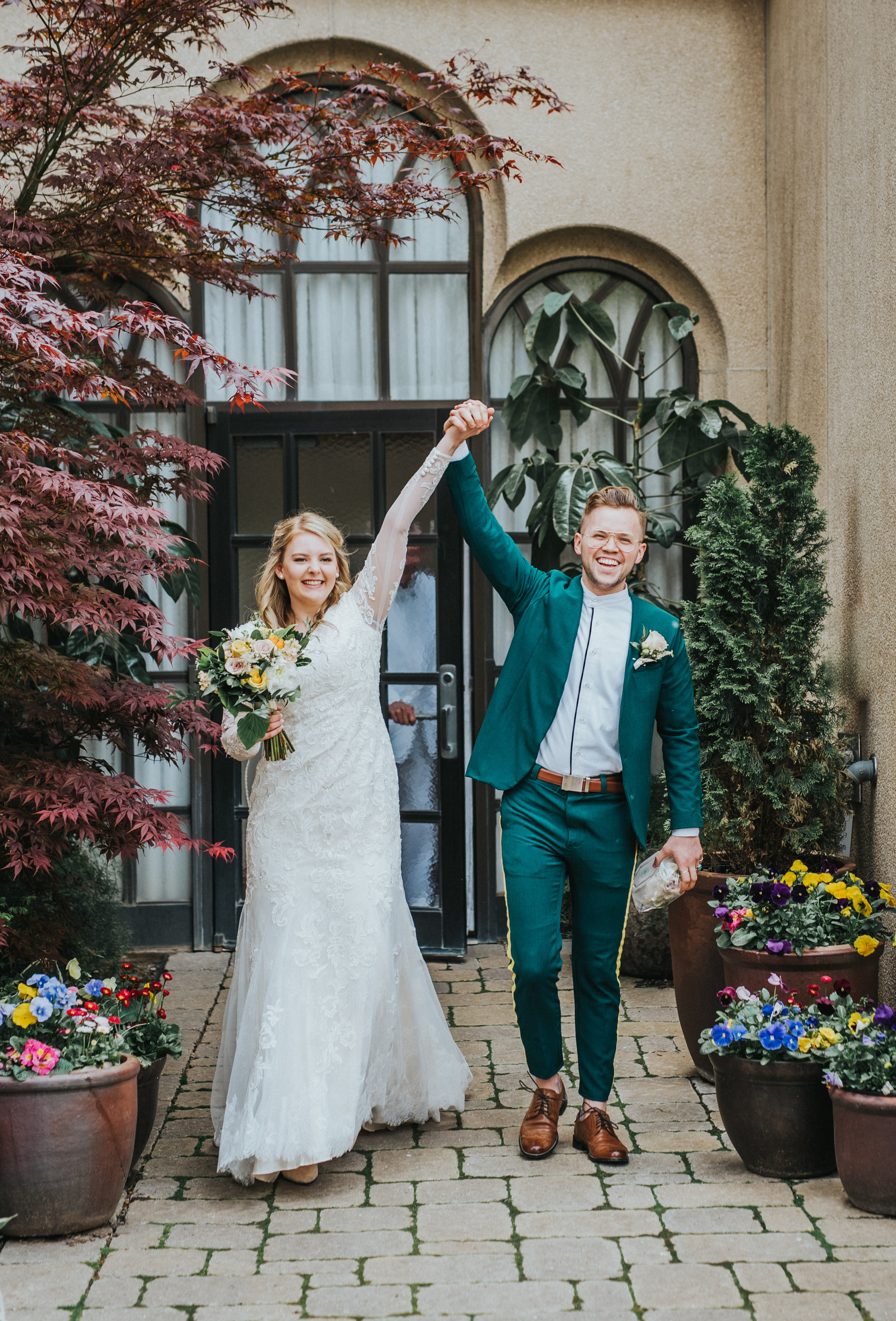  smiling laughing wedding exit professional logan utah wedding photographer logan utah lds temple wedding sealed for eternity holding hands smiling celebrating modest long sleeved lace wedding dress emerald green retro wedding suit yelloe wedding bou
