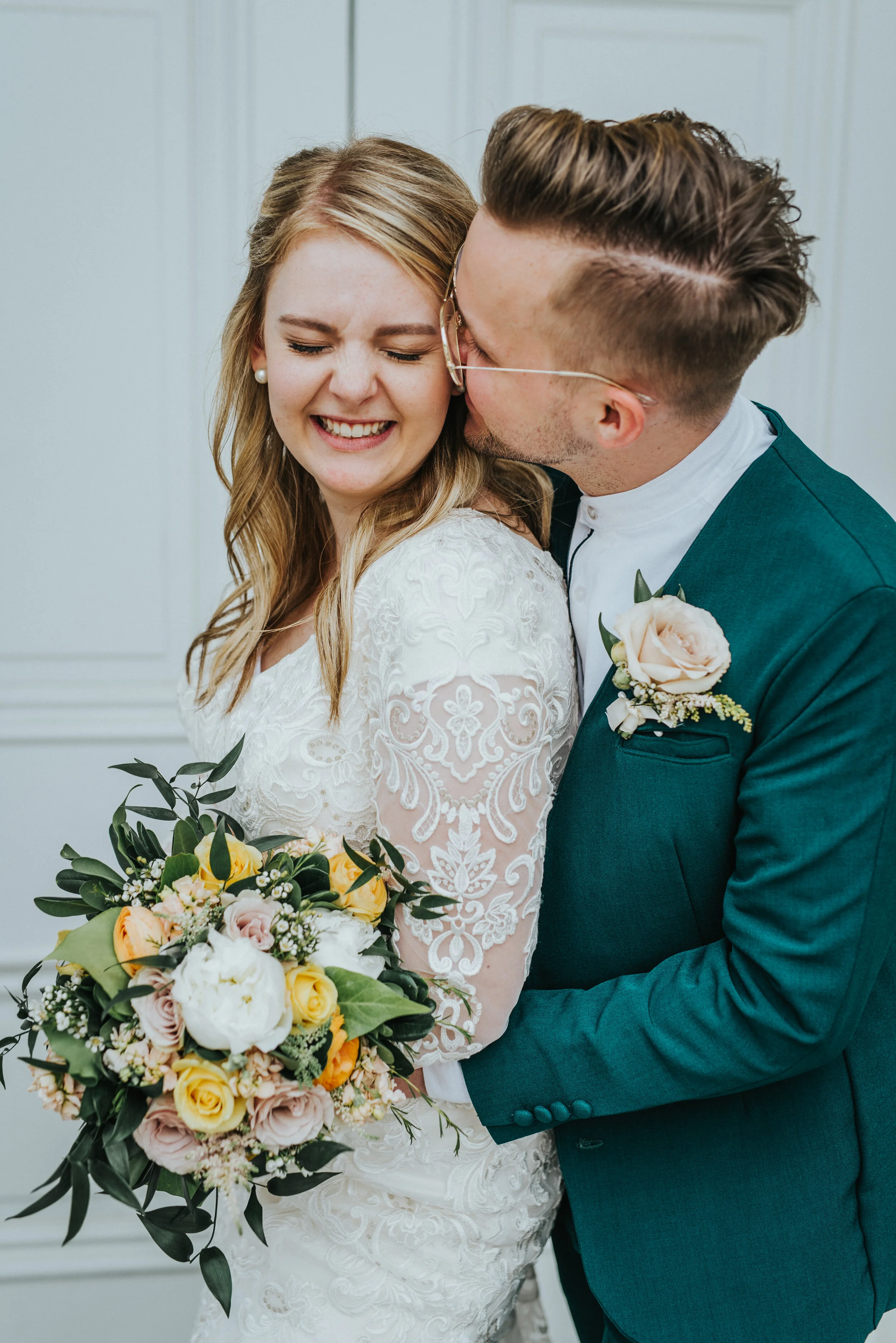  just married sealed for eternity logan utah lds temple white doors kissing cheeks hugging playful romantic loose half wedding updo vintage mens glasses retro emerald green wedding suit white and yellow wedding bouquet and boutonniere professional lo