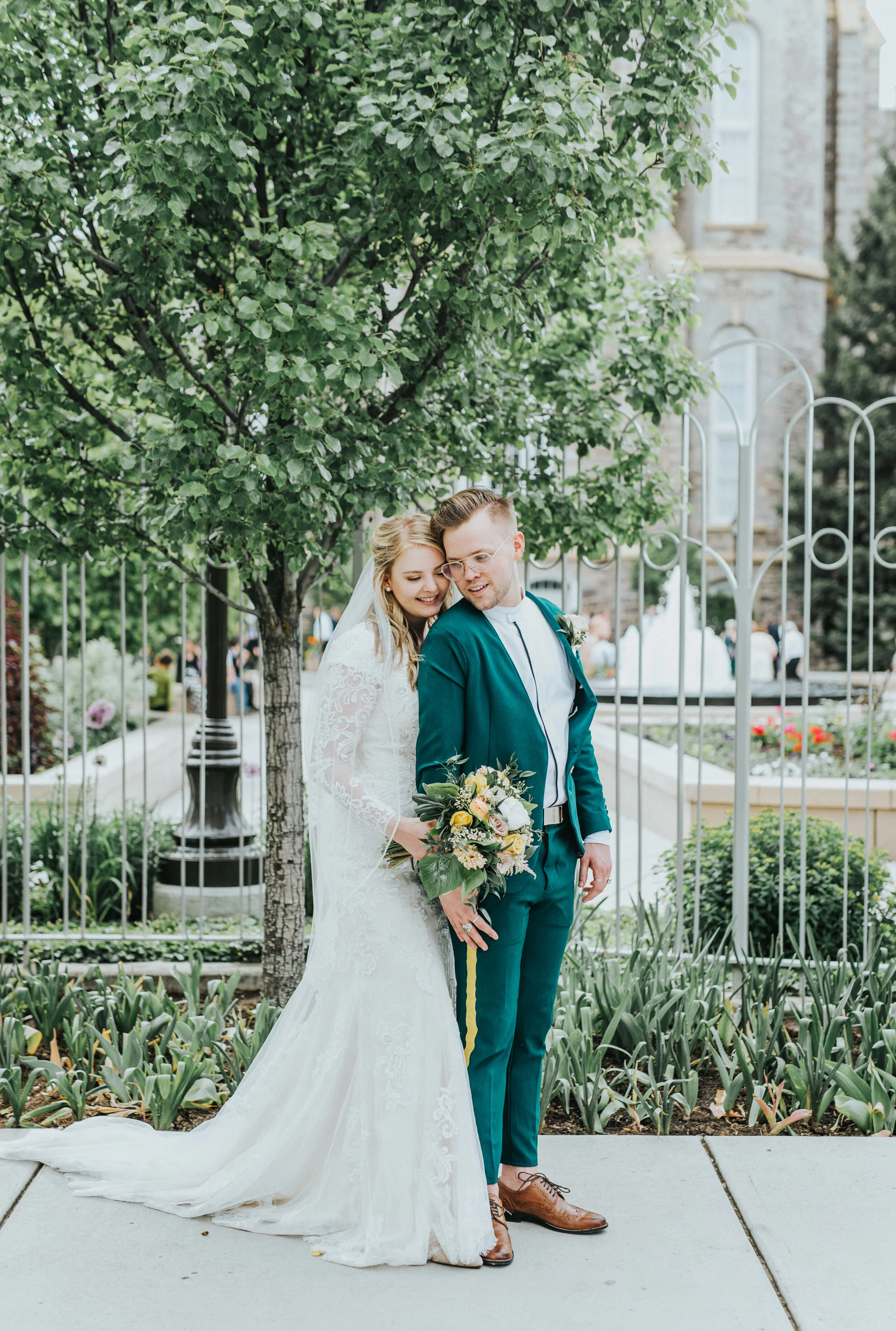  logan utah lds temple wedding grounds iron gate water fountains just married sealed for eternity hugging natural posing long sleeved lace wedding dress emerald green wedding suit professional cache valley utah wedding photographer #StationStudio #We