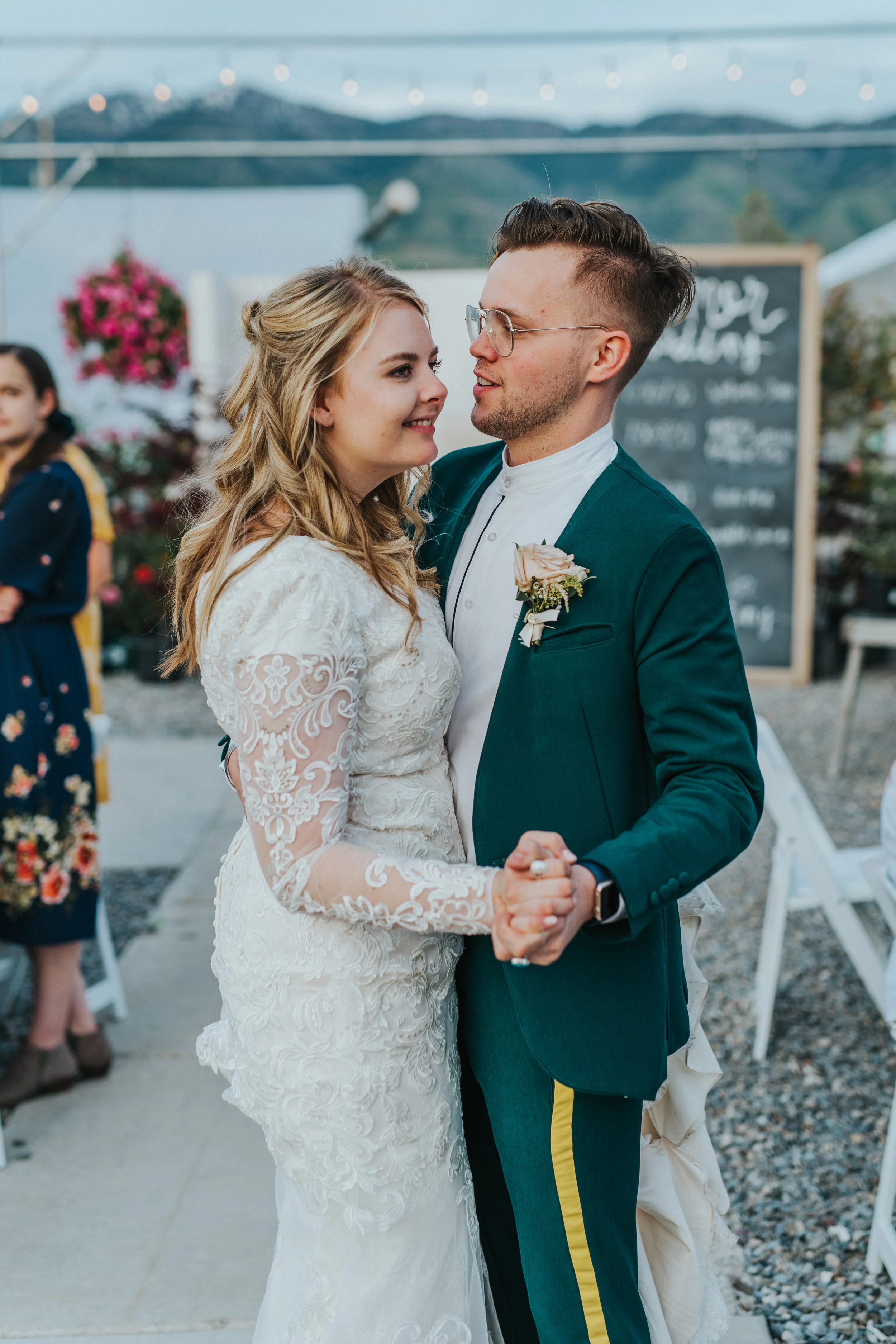  freckle farm outdoor wedding reception string lights chalk board reception decor first dance husband and wife smiling retro mens wedding suit emerald green modest lace wedding dress half updo wedding hair professional logan utah wedding photographer