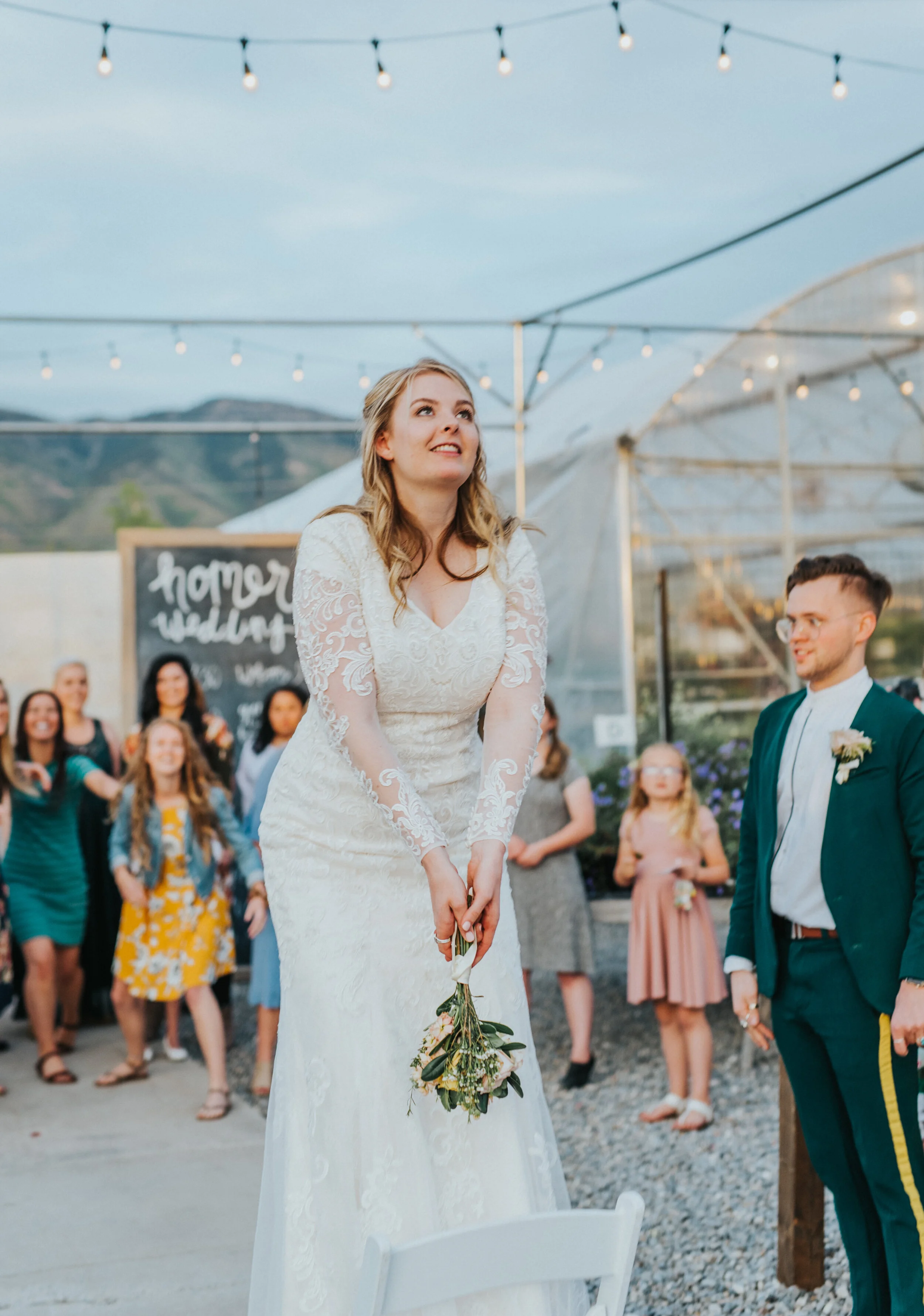  bouquet toss string lights outdoor wedding reception lds modest long sleeved lace wedding dress loose blond curls half updo professional logan utah wedding photographer cache valley utah freckle farm wedding reception #StationStudio #WeddingCeremony