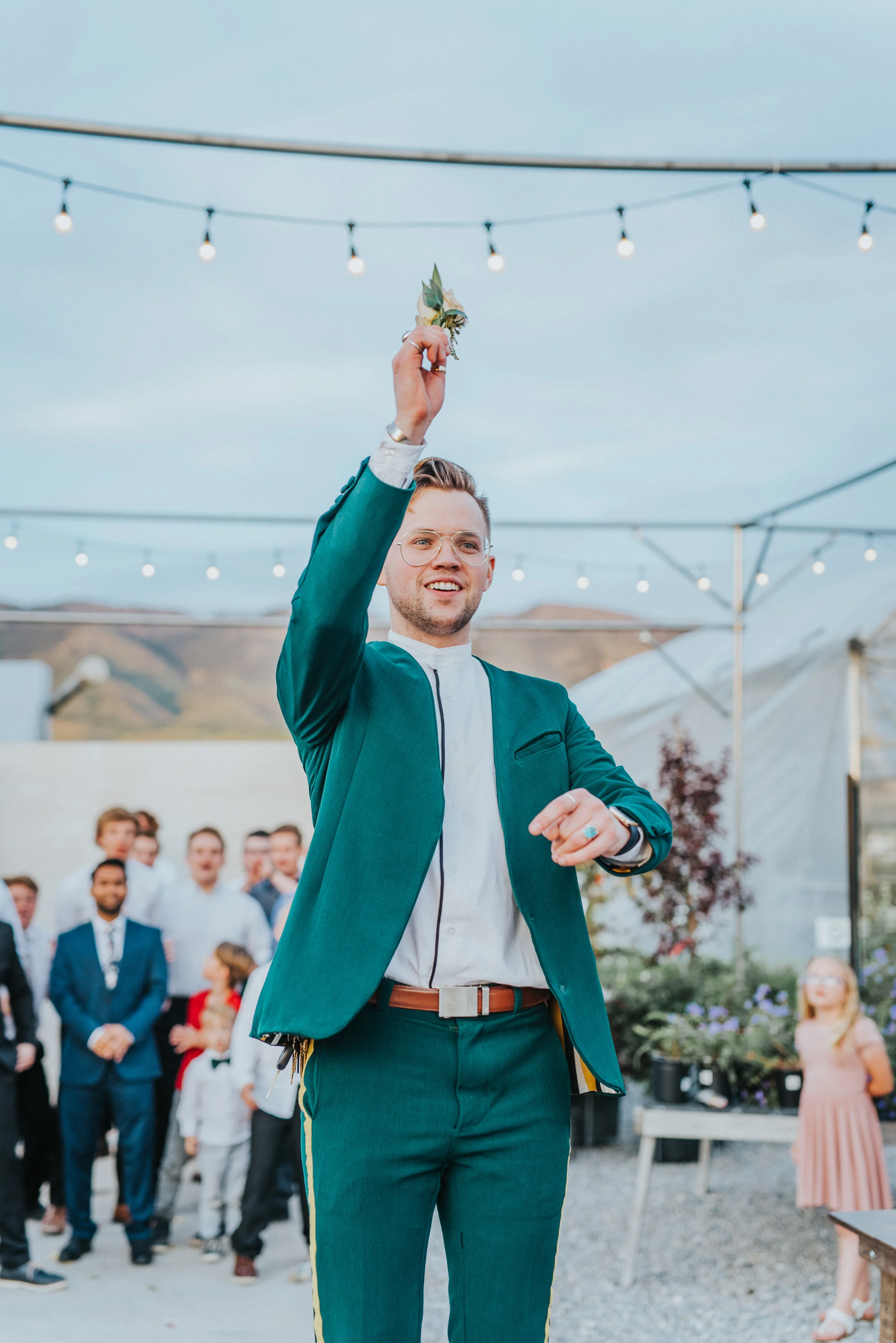  boutonniere toss string lights outdoor wedding reception happy mens turquoise ring cache valley professional wedding photographer candid moments freckle farm reception logan utah groom emerald green wedding suit retro #StationStudio #WeddingCeremony