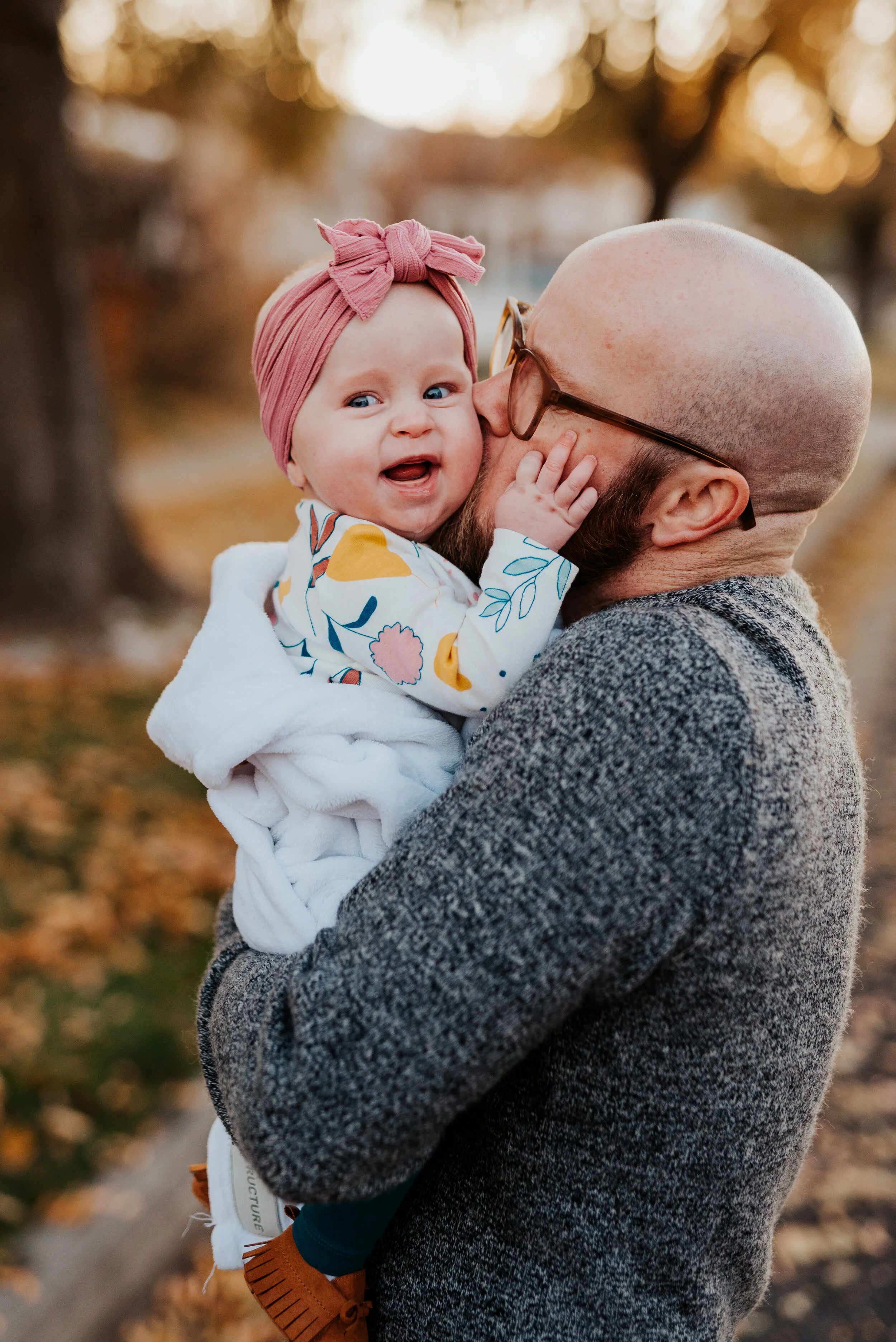  family photography infant photos dusty rose pink baby bling headband bow floral onsie daddy daughter photos kissing smiling baby authentic posing professional logan utah photographer fall photos holding baby wrapped in a blanket #loganutah #loganuta