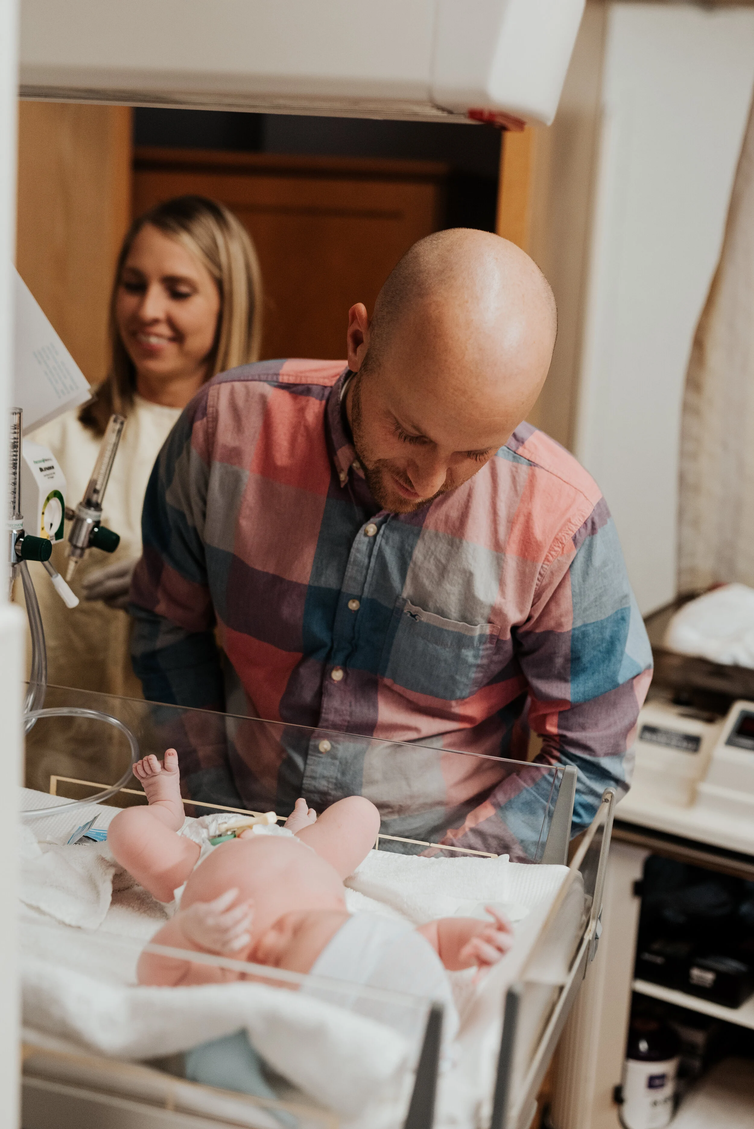  Dad gazing down adoringly at his beautiful newborn son in a hospital bassinet. newborn photographer in cache valley logan utah professional birth story photographer hospital pictures of a brand new baby birth photo session #kristialysephotography #n