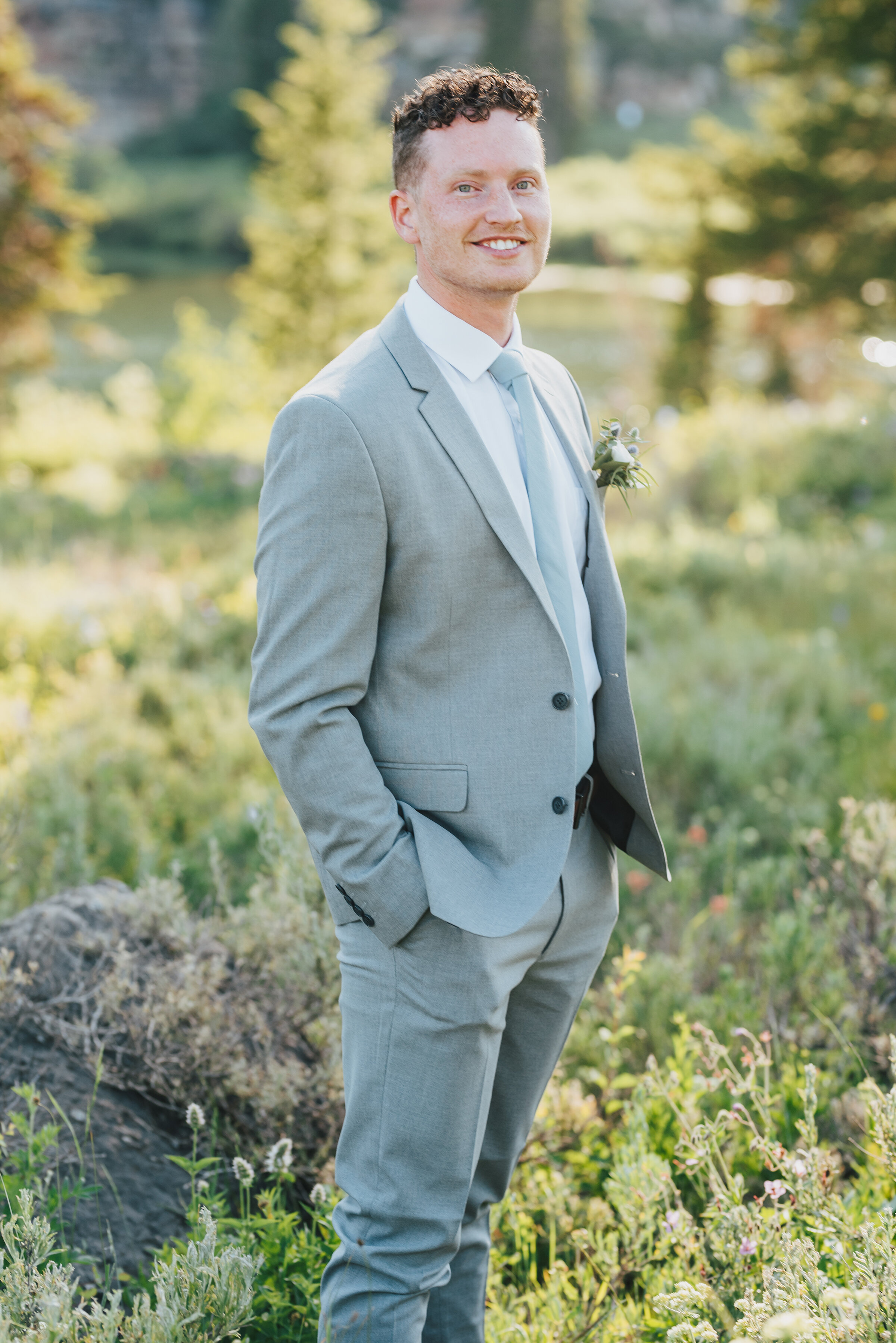  Handsome groom in grey suit surrounded by wild flowers for his formals up Logan canyon. Kristi Alyse photography Logan Utah wedding photographer forest nature dreamy formals Logan canyon Tony Grove scenic bridals Northern Utah photographer Utah brid