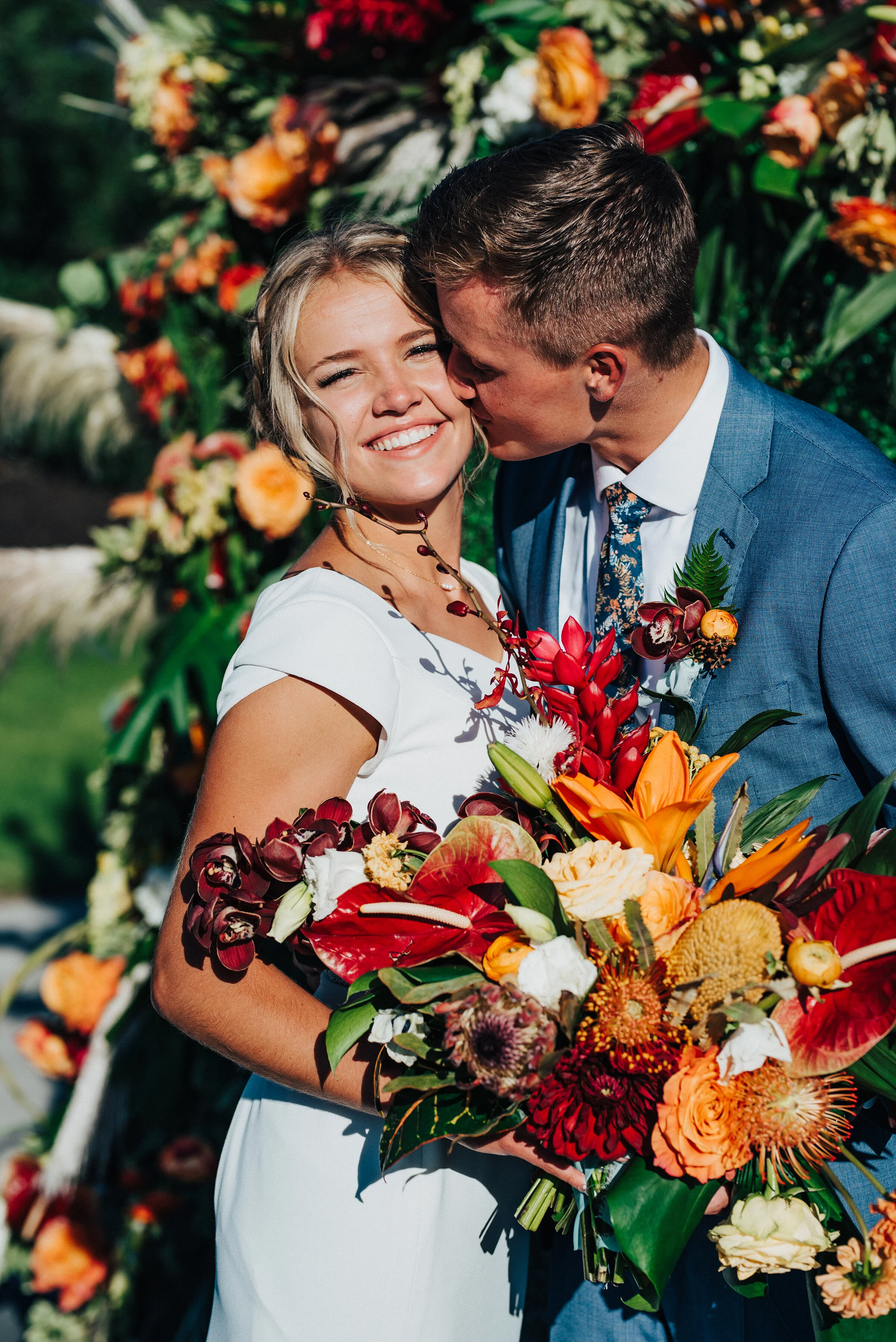Gorgeous sunlit bride and groom holding a beautifully handpicked spring bouquet at their outdoor wedding reception in Park City. Kristi Alyse Photography Logan Utah photographer Park City wedding photographer Drive-Thru wedding COVID wedding neon si…