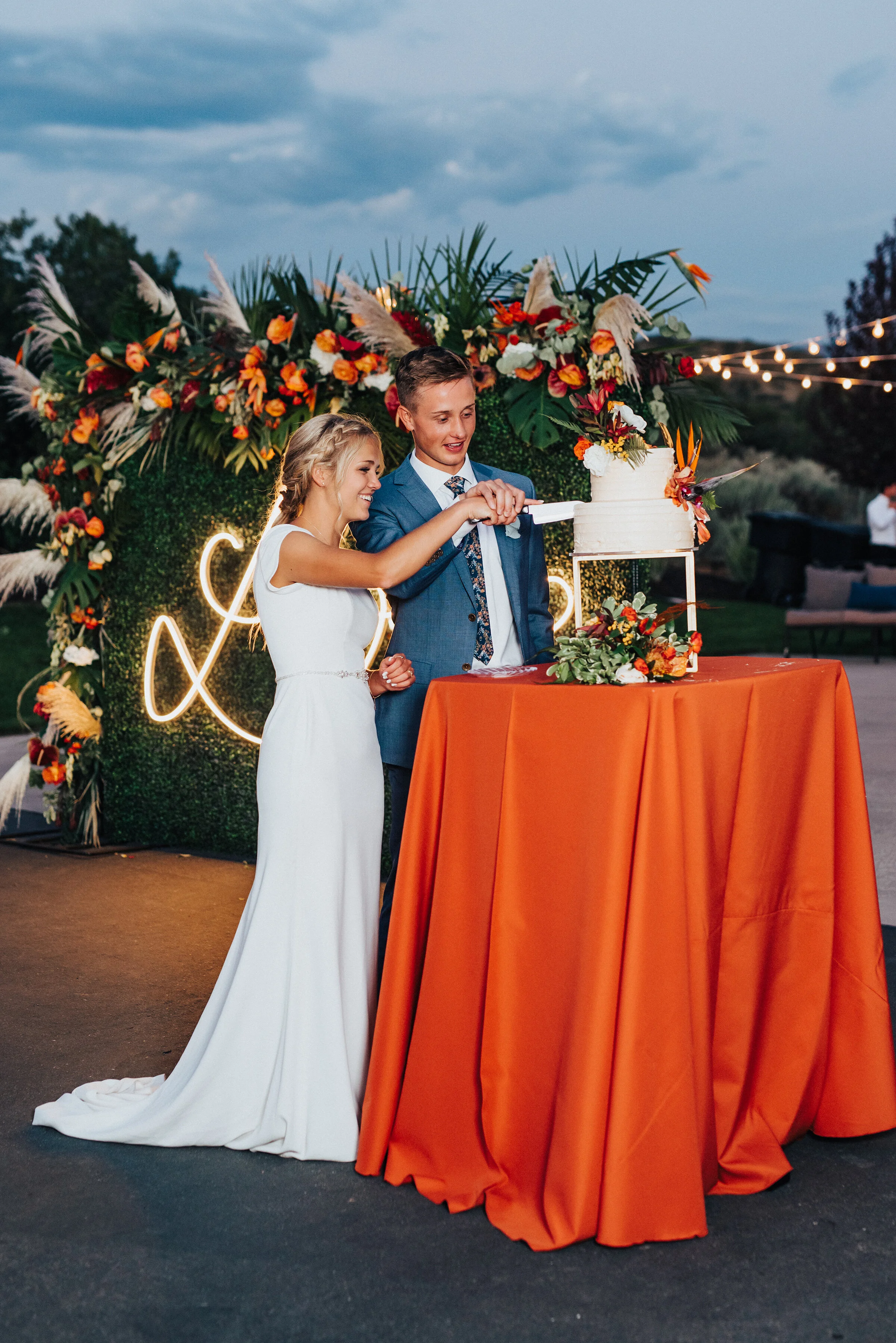  Stunning newlyweds cutting their wedding cake at this fun backyard wedding in Park City. Kristi Alyse Photography Logan Utah photographer Park City wedding photographer Drive-Thru wedding COVID wedding neon signs socially distant wedding bride and g