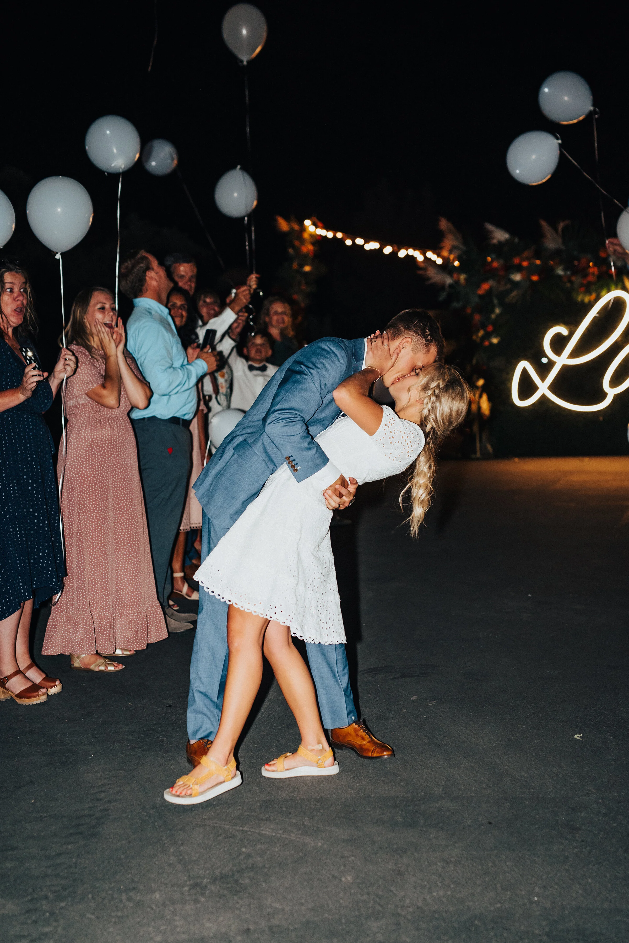 Newlyweds sharing one final kiss before they are on their way to their honeymoon. Kristi Alyse Photography Logan Utah photographer Park City wedding photographer Drive-Thru wedding COVID wedding neon signs socially distant wedding exit bride and gro…