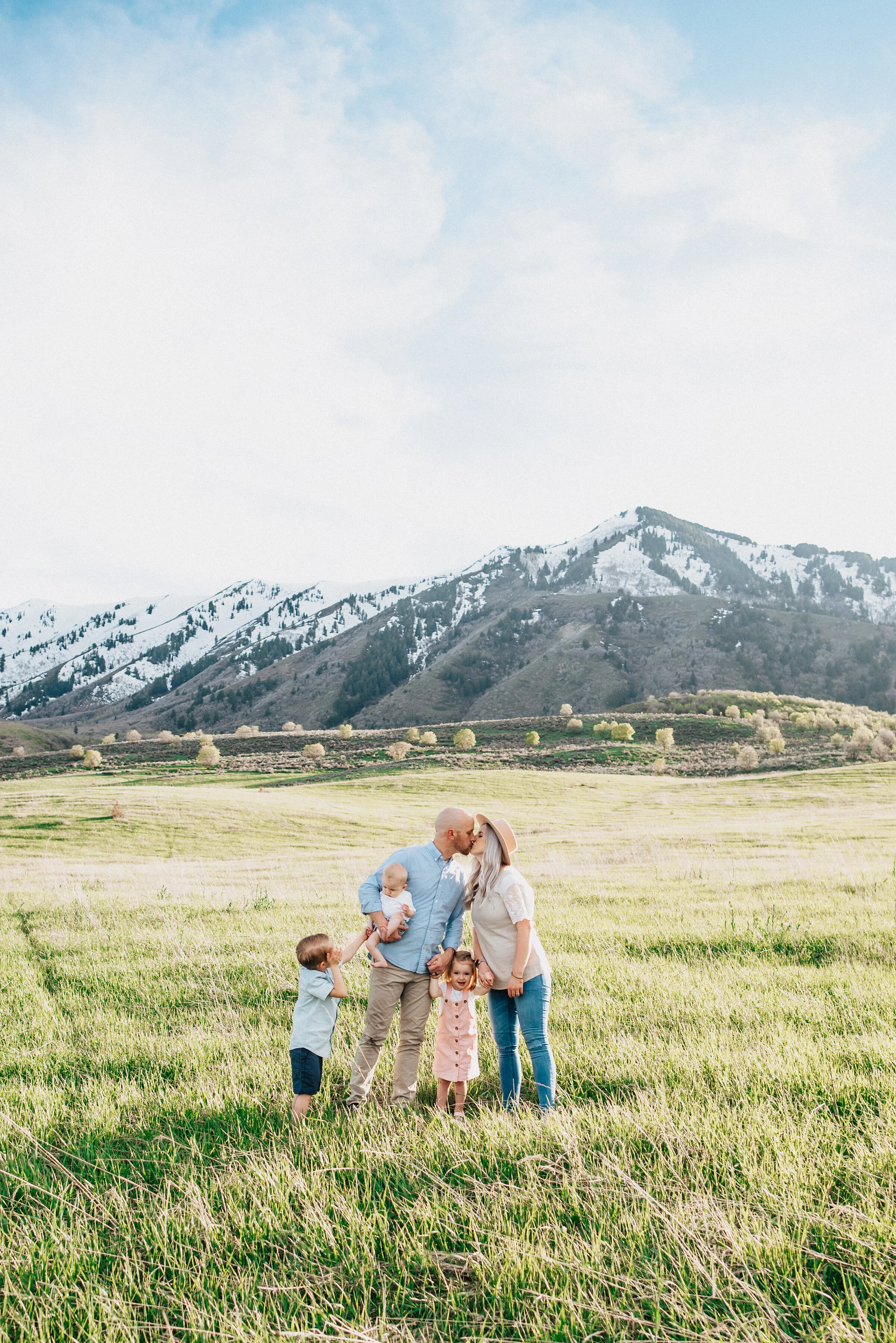  Mom and dad kiss while small children laugh in beautiful logan utah photoshoot. Kristi Alyse Photography mountain themed family photoshoot mom and dad kissing family photography family portraits with small children utah photographer #kristialyse #kr