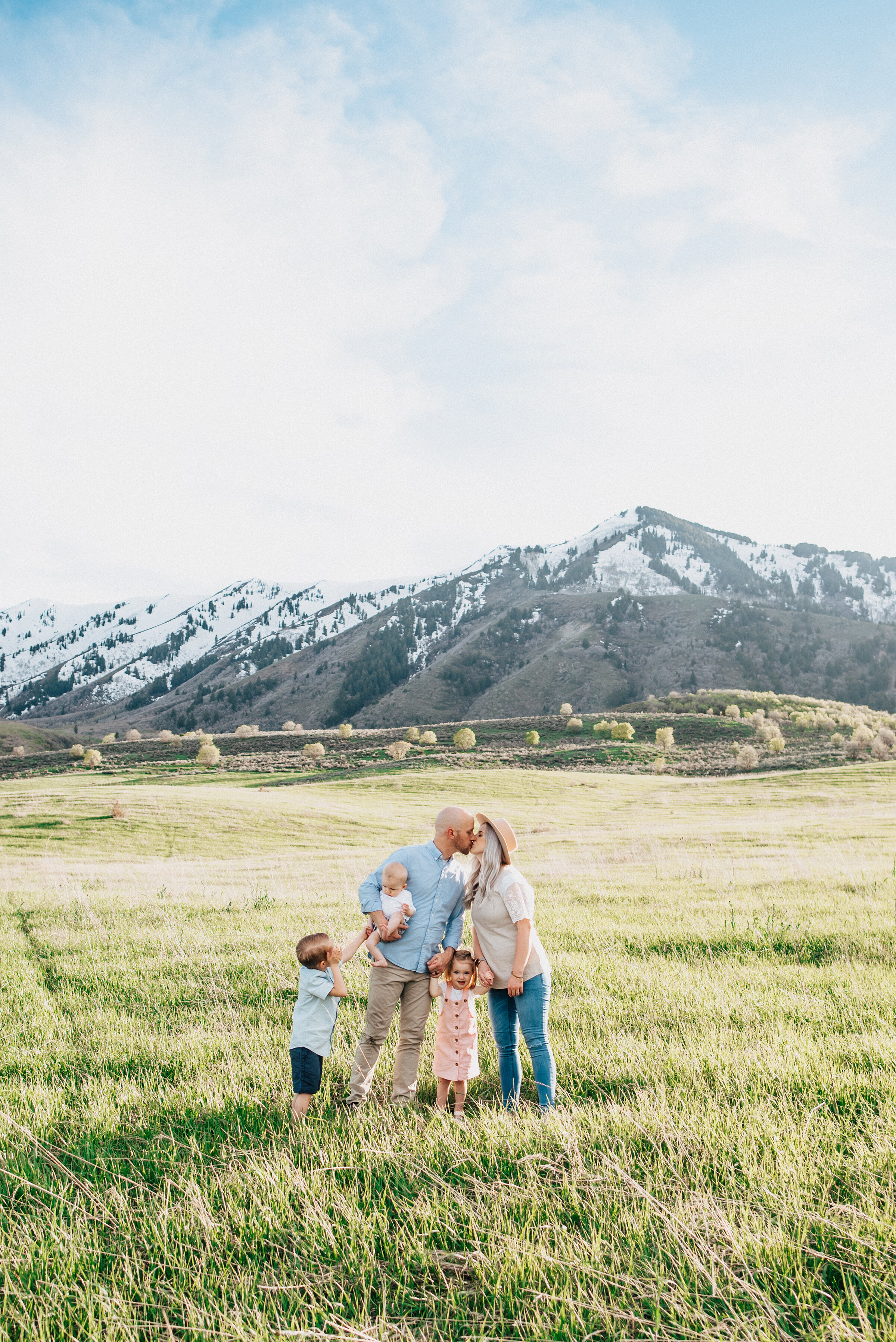  Mom and dad kiss while small children laugh in beautiful logan utah photoshoot. Kristi Alyse Photography mountain themed family photoshoot mom and dad kissing family photography family portraits with small children utah photographer #kristialyse #kristialysephotography #momanddad #familylove #happymarriage #utahphotography #loganutahphotos #mountainfamilyphotos #familyphotoinspo #familyphotoshoot 
