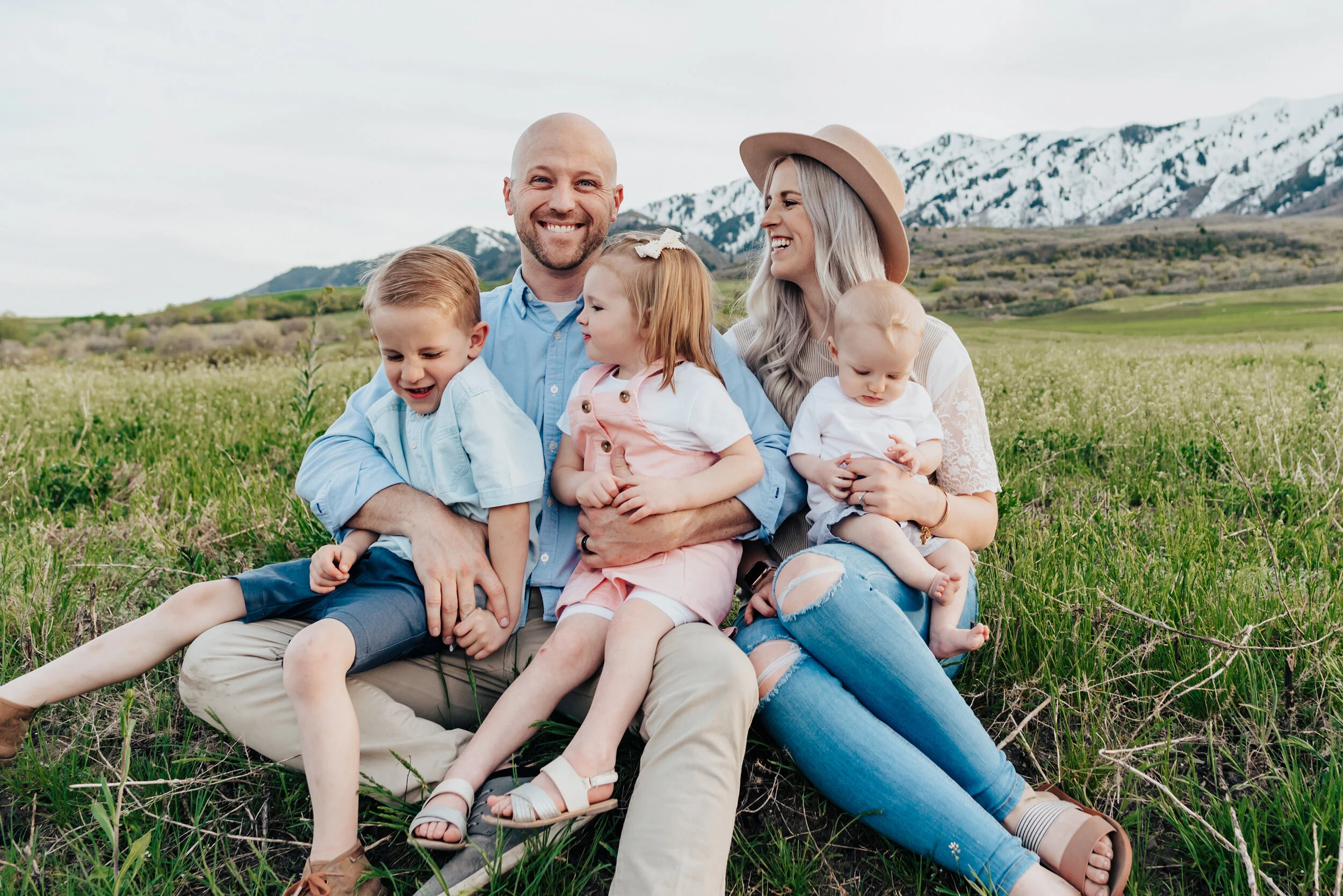 Dad and mom smile at each other with their children on their lap during a wellsville utah family photoshoot. Family memories young family pose ideas mountain family photos utah photographer cache valley photography #wellsvilleut family photo inspira…