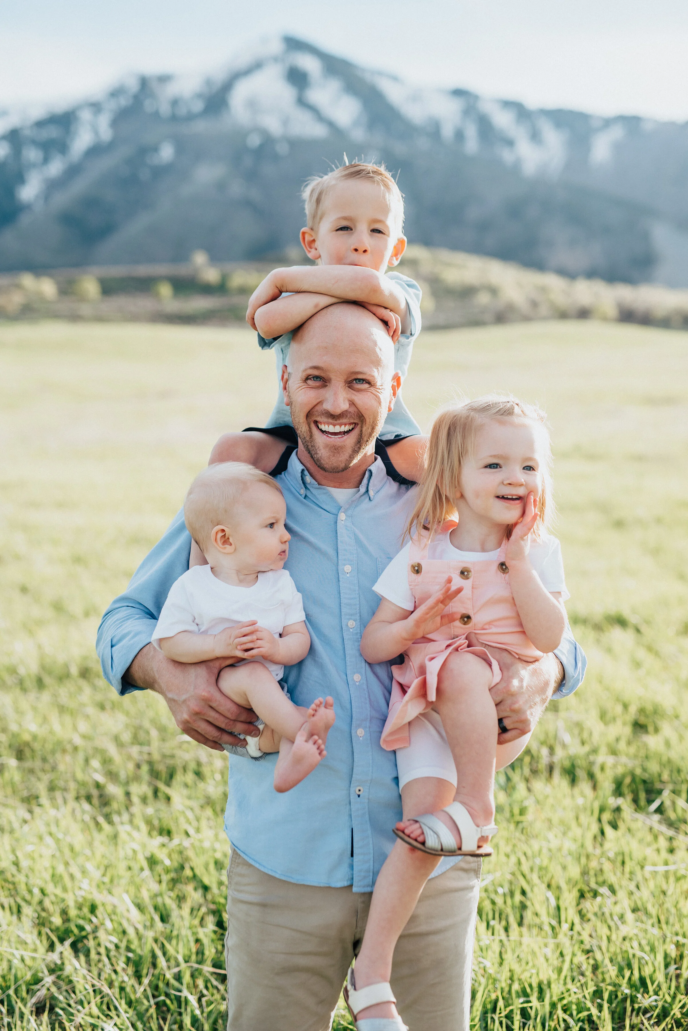  Dad holds all three of his children during a wellsville utah family photoshoot. Daddy smiles with all children family memories young family pose ideas mountain family photos utah photographer cache valley photography #wellsvilleut family photo inspi