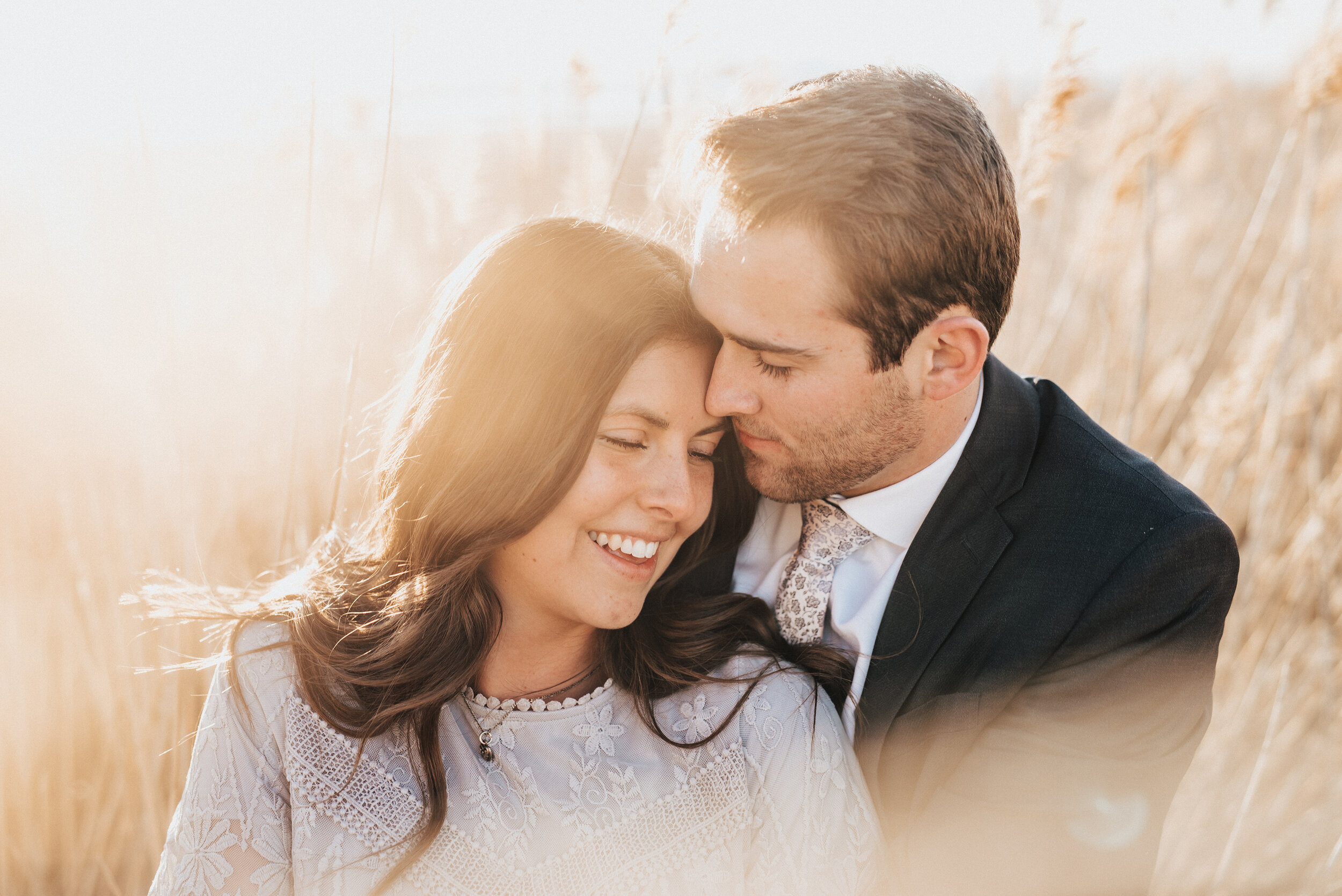 Couple smiles among grain in Magna Utah during a blissful engagement session. Engagement photo inspiration utah engagement photoshoot outdoor engagement session utah wedding photographer wedding and engagement sessions best engagement photographer c…