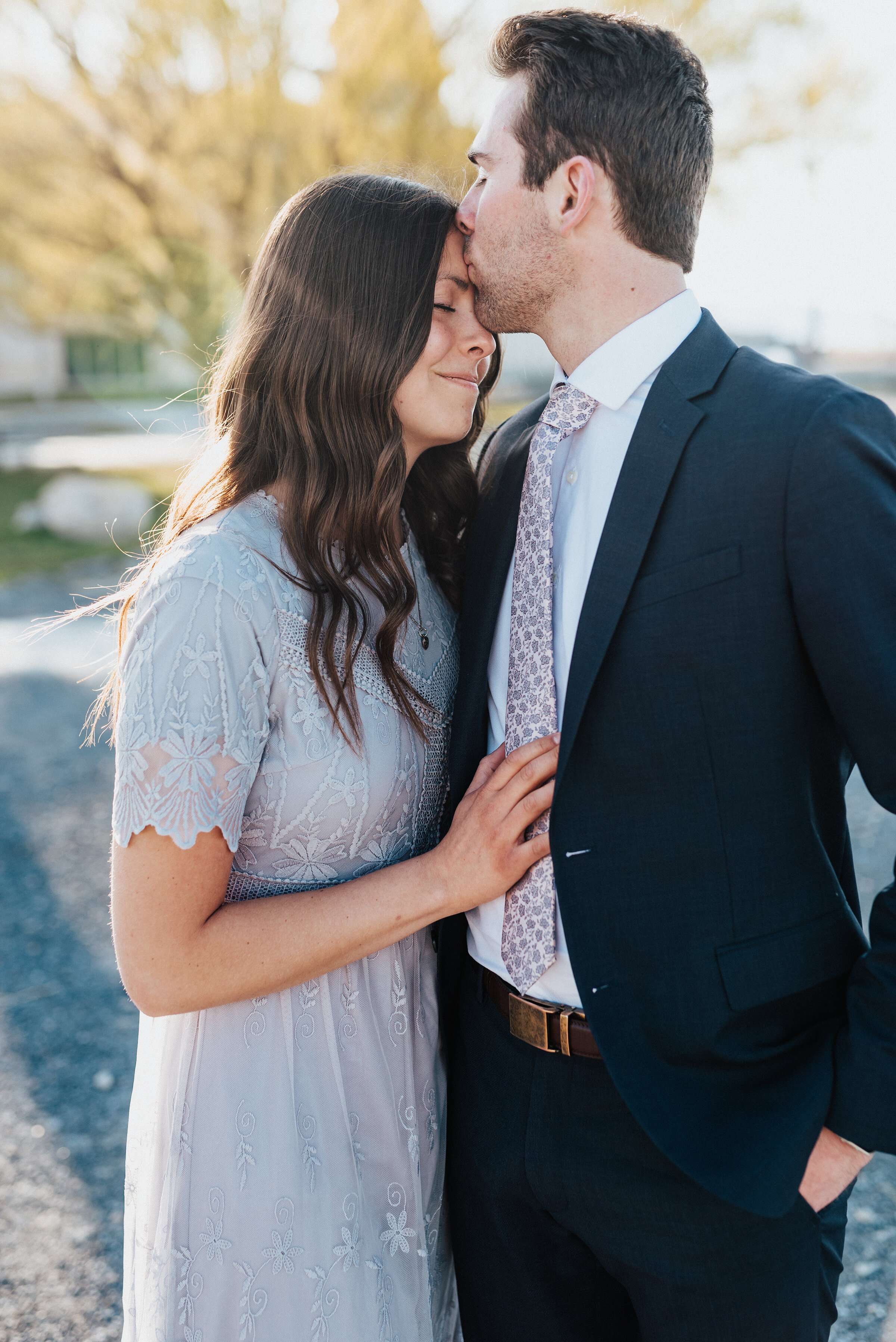  Man kisses his future brides forehead in Magna Utah engagement session at the Great Saltair and the Salt Flats. Engagement photoshoot at Great Saltair Salt Flats photography engagement outdoor location ideas grey lace engagement couple outfit ideas 