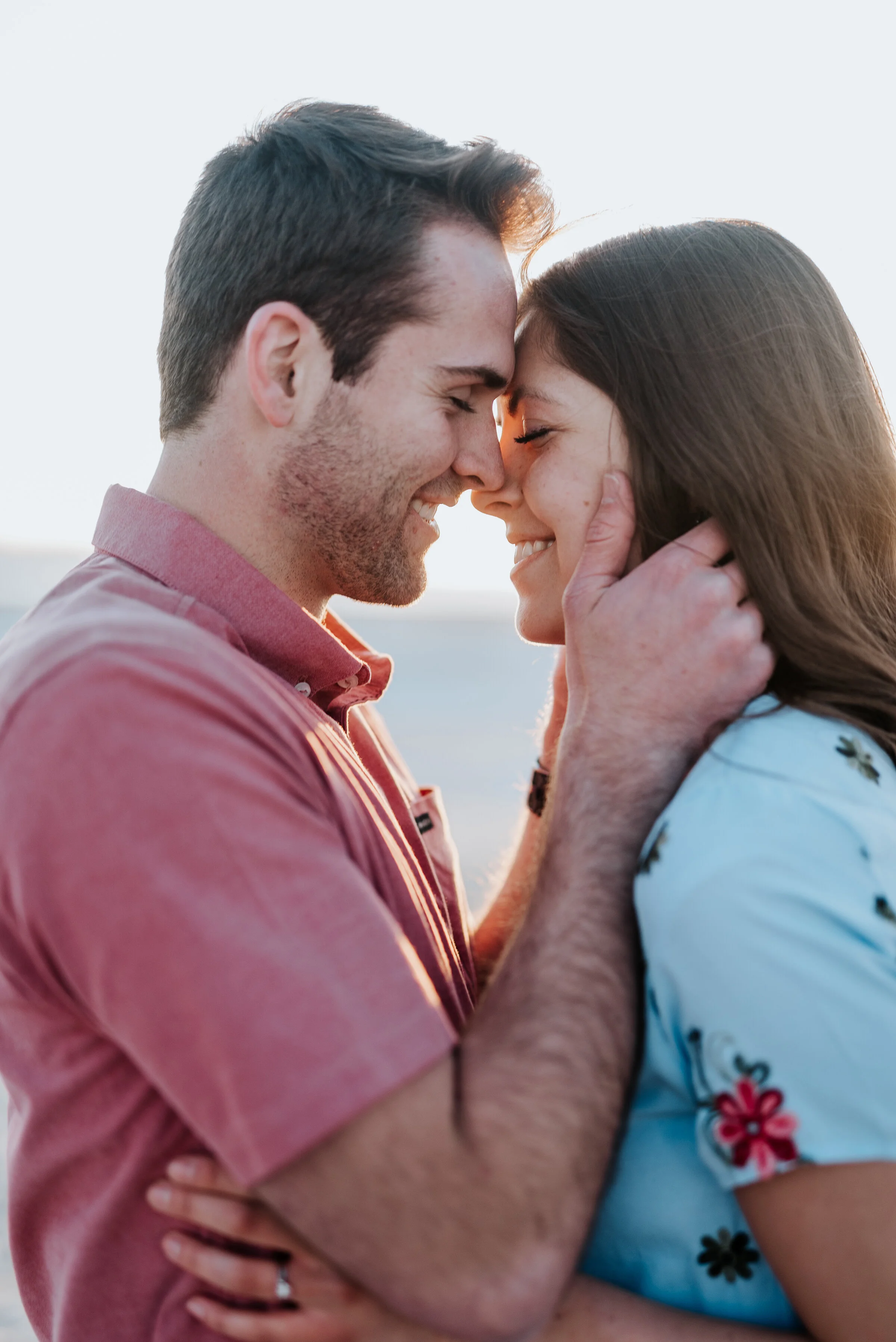  Happy, laughing couple pose with a lens flare behind them during their engagement photoshoot in Magna, Utah. Best wedding and engagement photographer Magna Utah Saltair Salt flats photography couple poses ideas engagement inspiration Kristi Alyse Ph