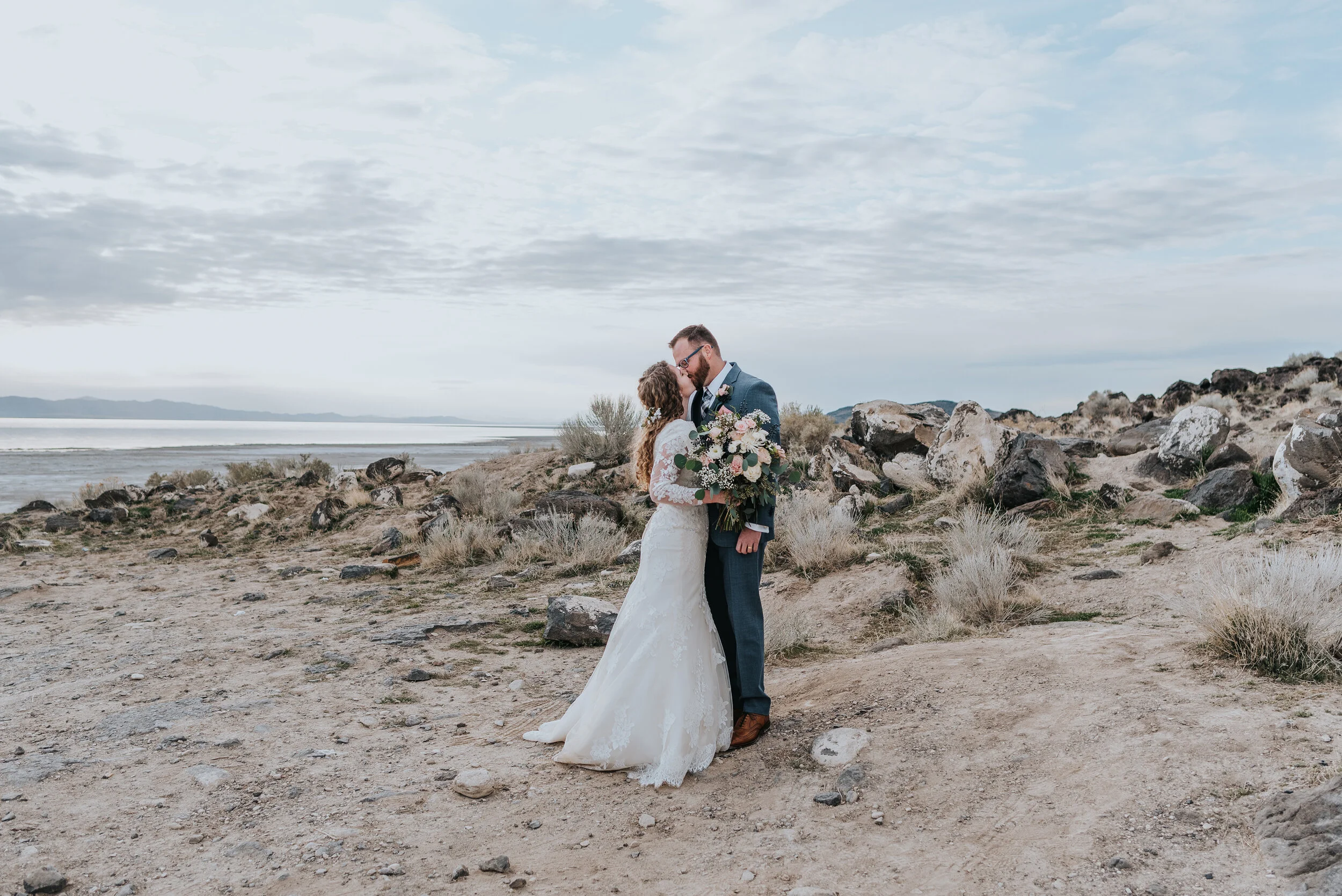  Bride and groom to be exchanging a kiss during their wedding formals at the Spiral Jetty in northern Utah. wedding formal photoshoot in Spiral Jetty Northern Utah Great Salt Lake photography wedding formals natural photo aesthetic bride and groom #s