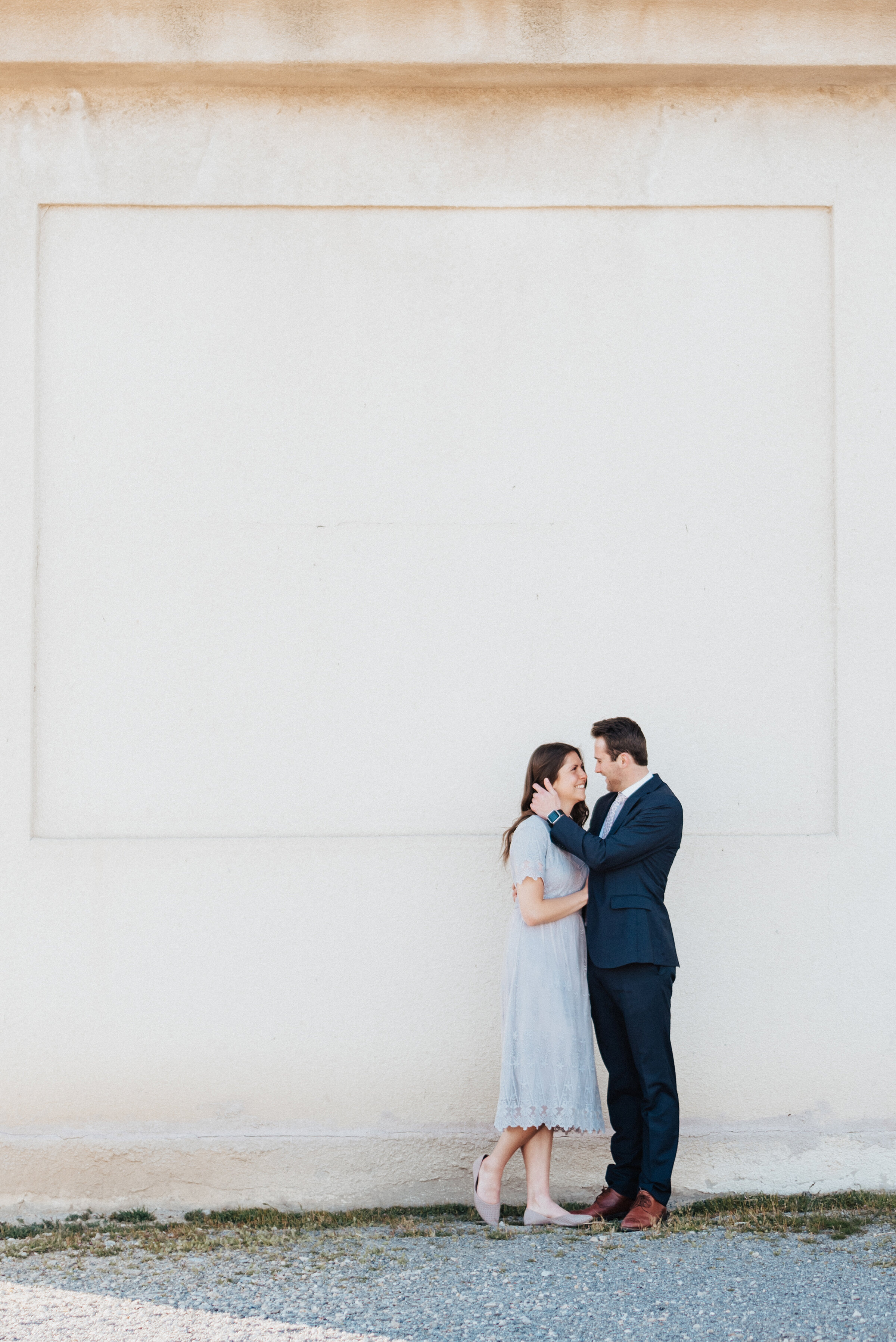  Beautiful matching couple pose in front of a large textured wall during their utah engagement photoshoot session with Kristi Alyse Photography. Utah's best photographer family photography gray lace dress outfit ideas for engagements utah engagement 