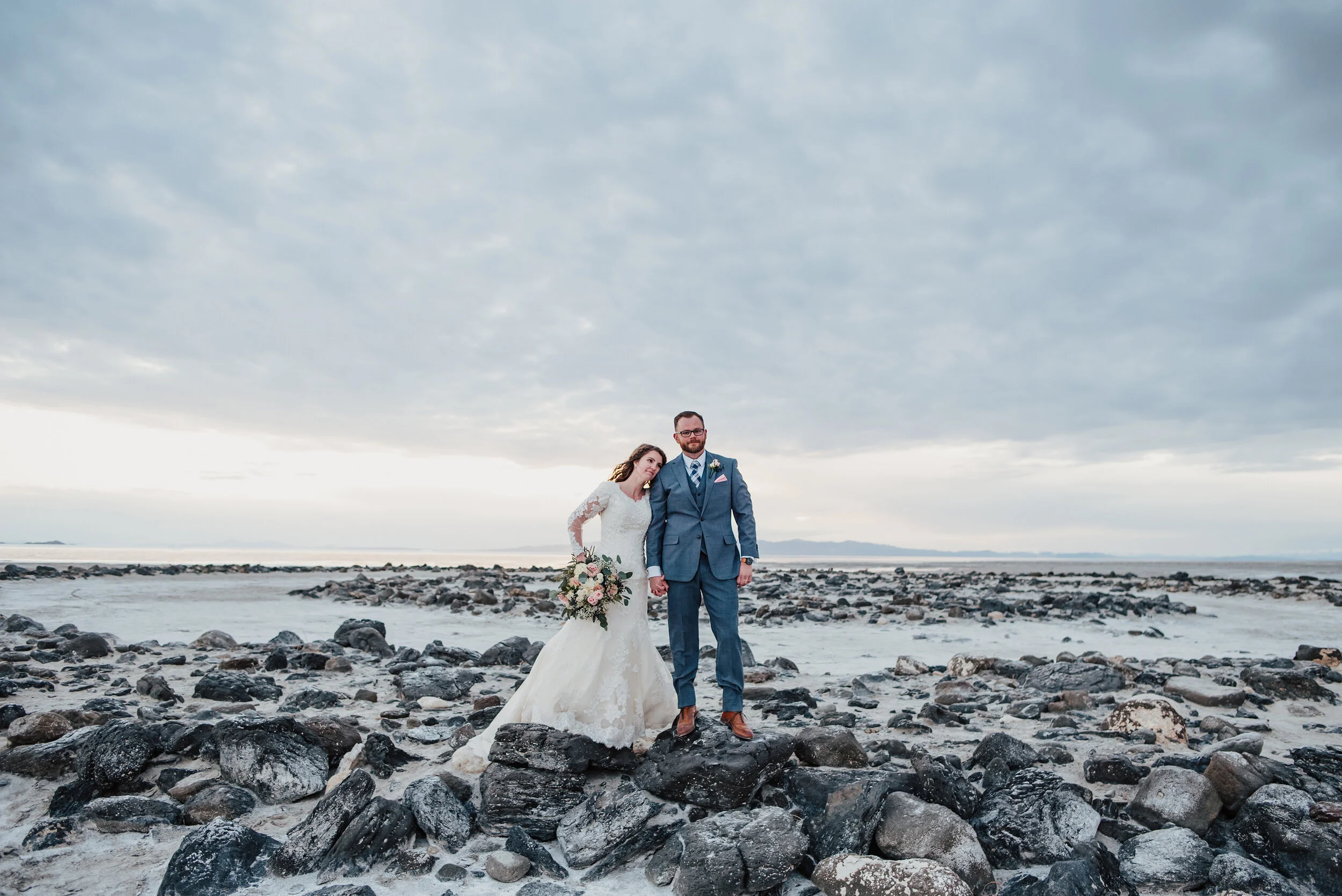  Standing on the rocks at the Spiral Jetty, this bride and groom took in all of the natural elements available during their wedding formal photoshoot. Spiral Jetty Northern Utah Great Salt Lake photography wedding formals natural photo aesthetic brid