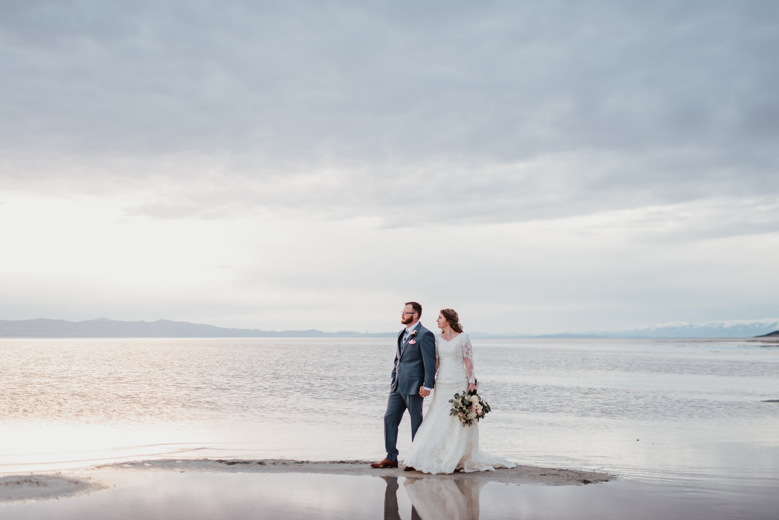  Walking along the sand as the sun set behind the Spiral Jetty near the Great Salt Lake. wedding formal photoshoot in Spiral Jetty Northern Utah Great Salt Lake photography wedding formals natural photo aesthetic bride and groom #spiraljetty #utahphotography #weddingformals #gettingmarried #weddingattire #utahwedding #greatoutdoorswedding #weddingformalsphotoshoot #naturalbeauty 