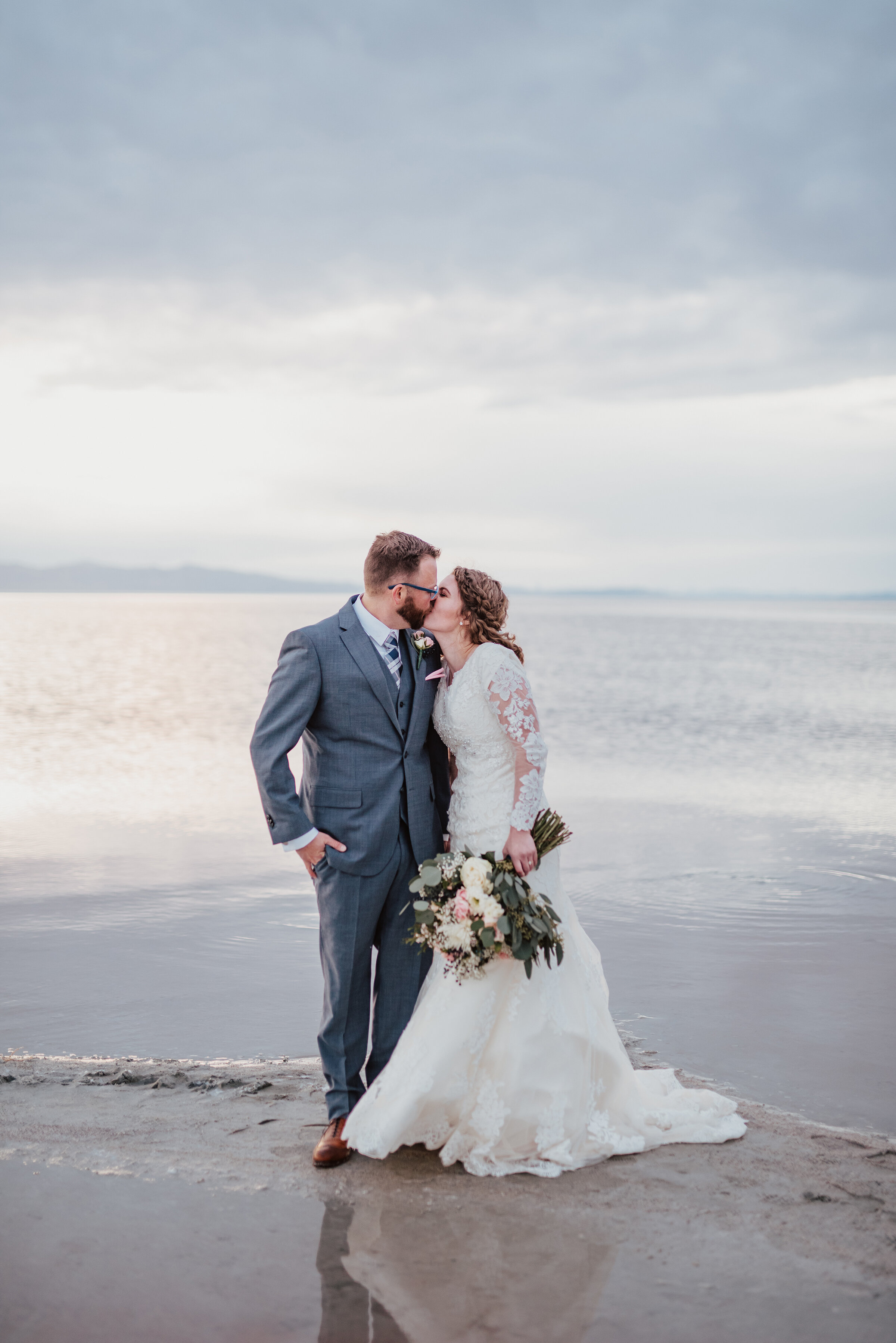  The bride and groom sharing a kiss at the Great Salt Lake Spiral Jetty as they walked through the sand. Wedding formal photoshoot in Spiral Jetty Northern Utah Great Salt Lake photography wedding formals natural photo aesthetic bride and groom #spir