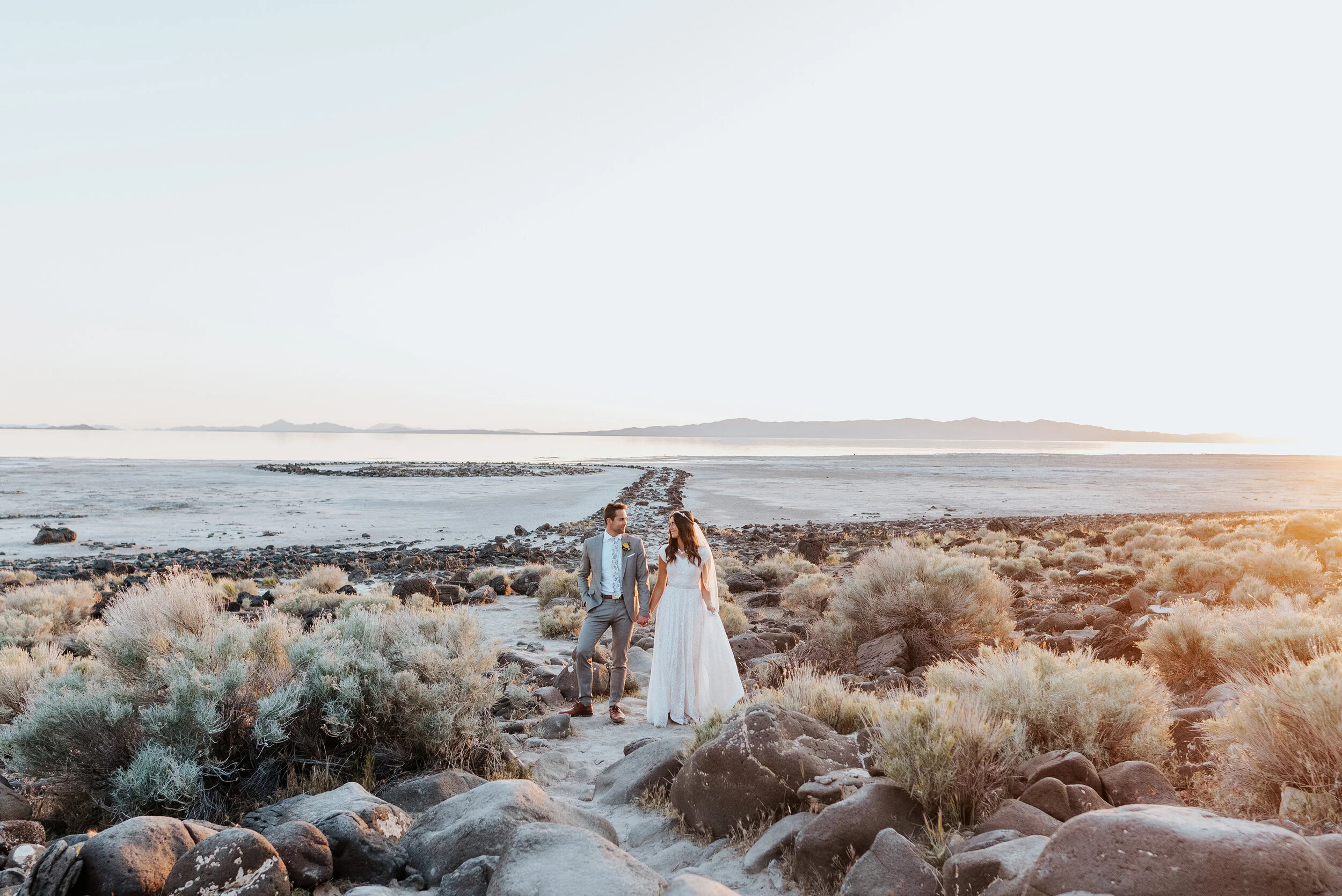  With the last glimpses of the sun shining just beyond the waters edge, this bride and groom stood with a stunning backdrop and held each other with excitement. wedding formal session utah wedding photographer formal session #spiraljetty #GreatSaltLa
