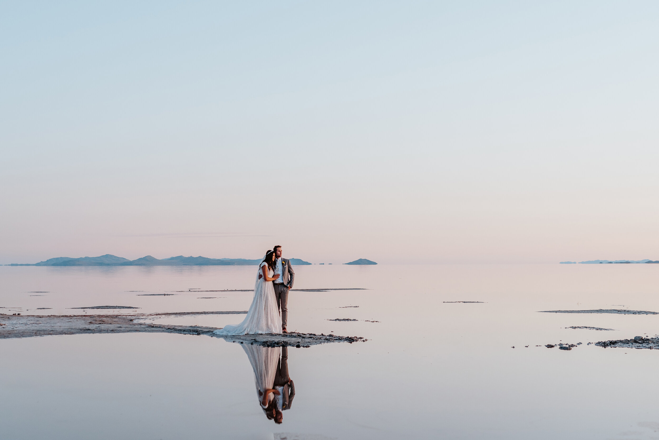 The bride and groom were surrounded by water as their reflection is captured flawlessly without any wind at the Great Salt Lakes. #spiraljetty #GreatSaltLake #formalsession #SaltFlats #sunsetphotosession #NorthernUtah #weddingphotographer #formalpho…