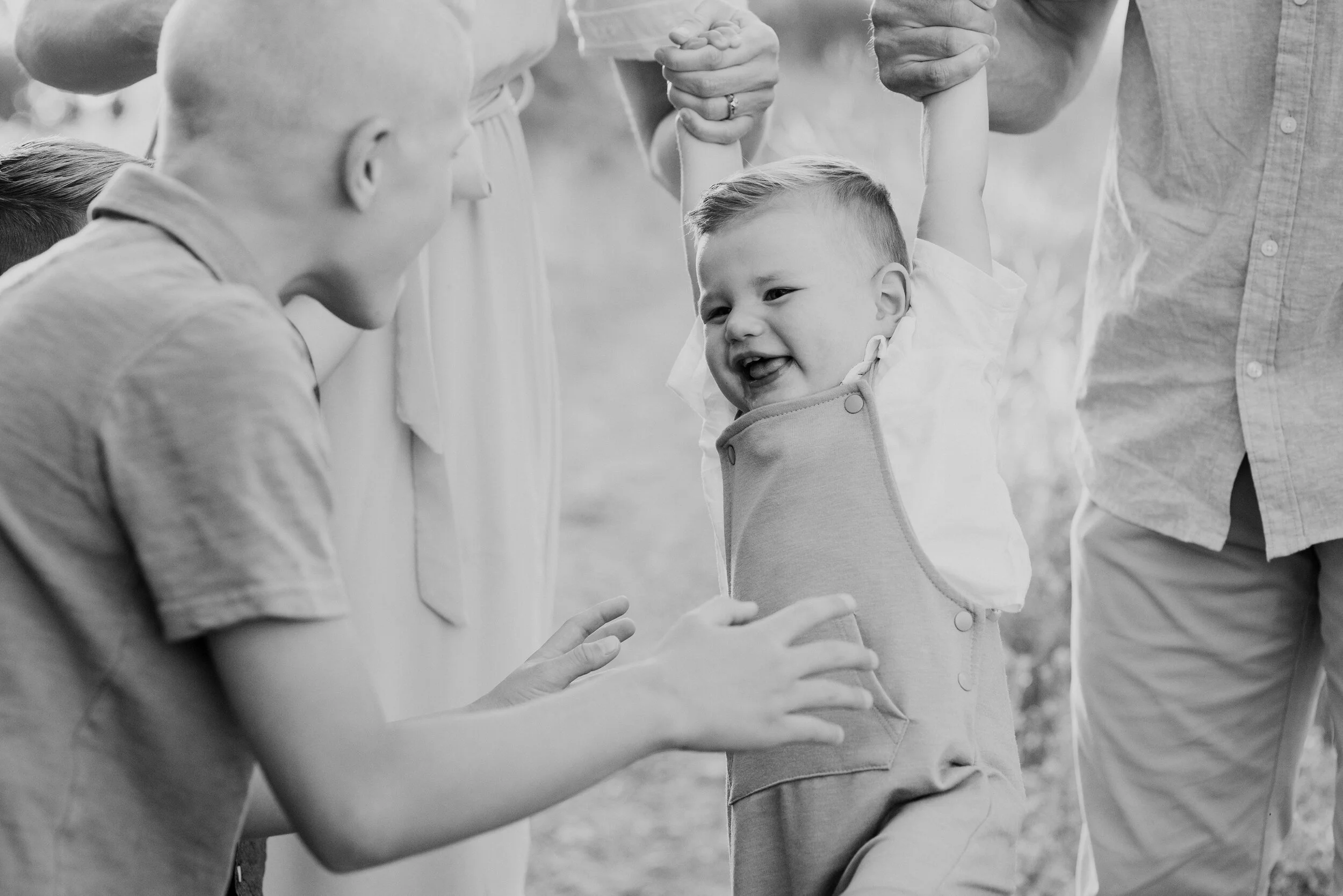 Tender moment of an older brother tickling his youngest brother suspended by his parents in Providence Canyon, UT. Black and white style family photography outdoor family photos brothers showing affection laughing toddler #providencecanyon #utahphot…
