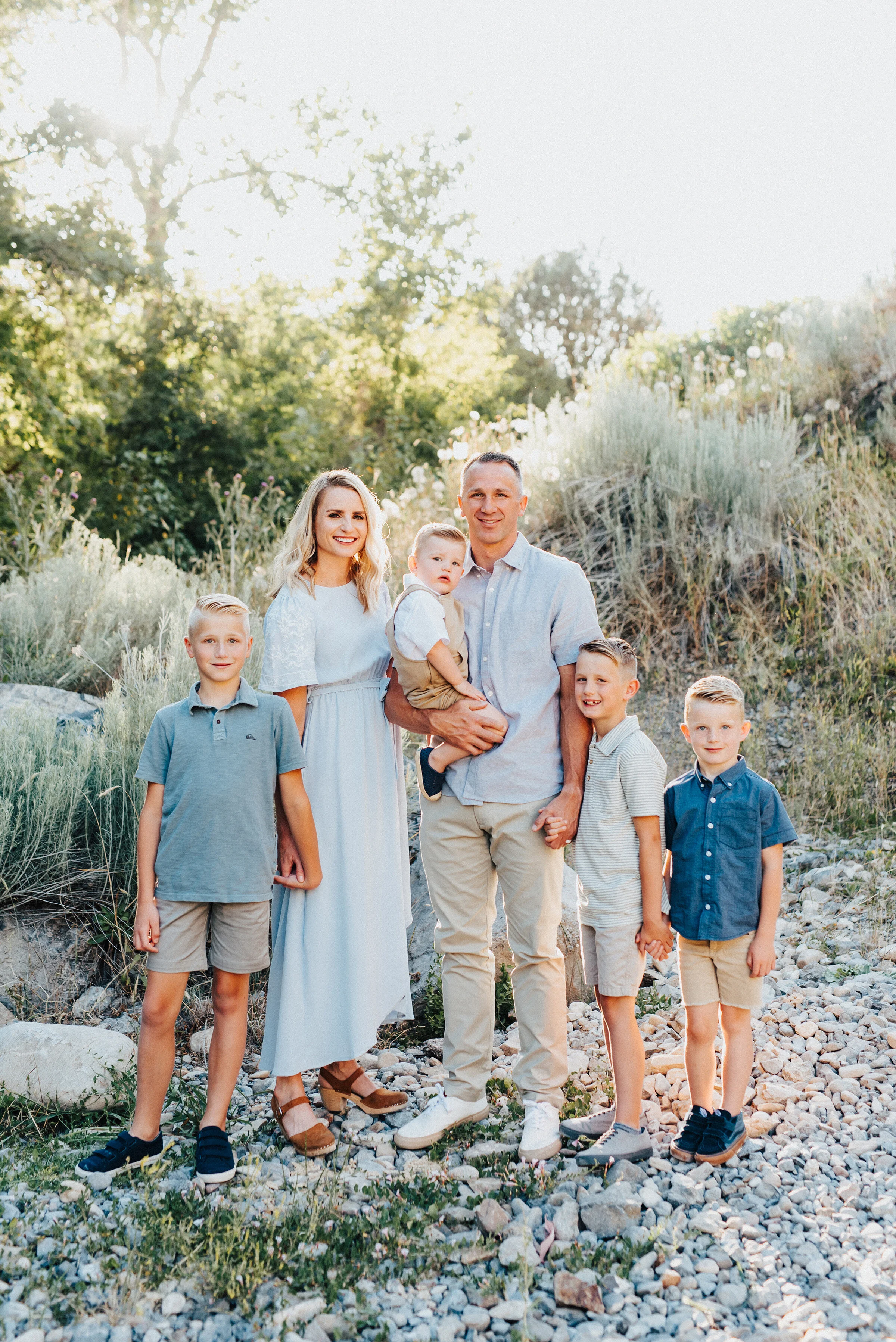  Elegant outdoor photoshoot featuring a beautiful family holding hands and gently smiling on a rocky hillside in Providence Canyon, UT. Light blue and khakis soft outdoor setting family photoshoot holding hands formal smiles  #providencecanyon #utahp