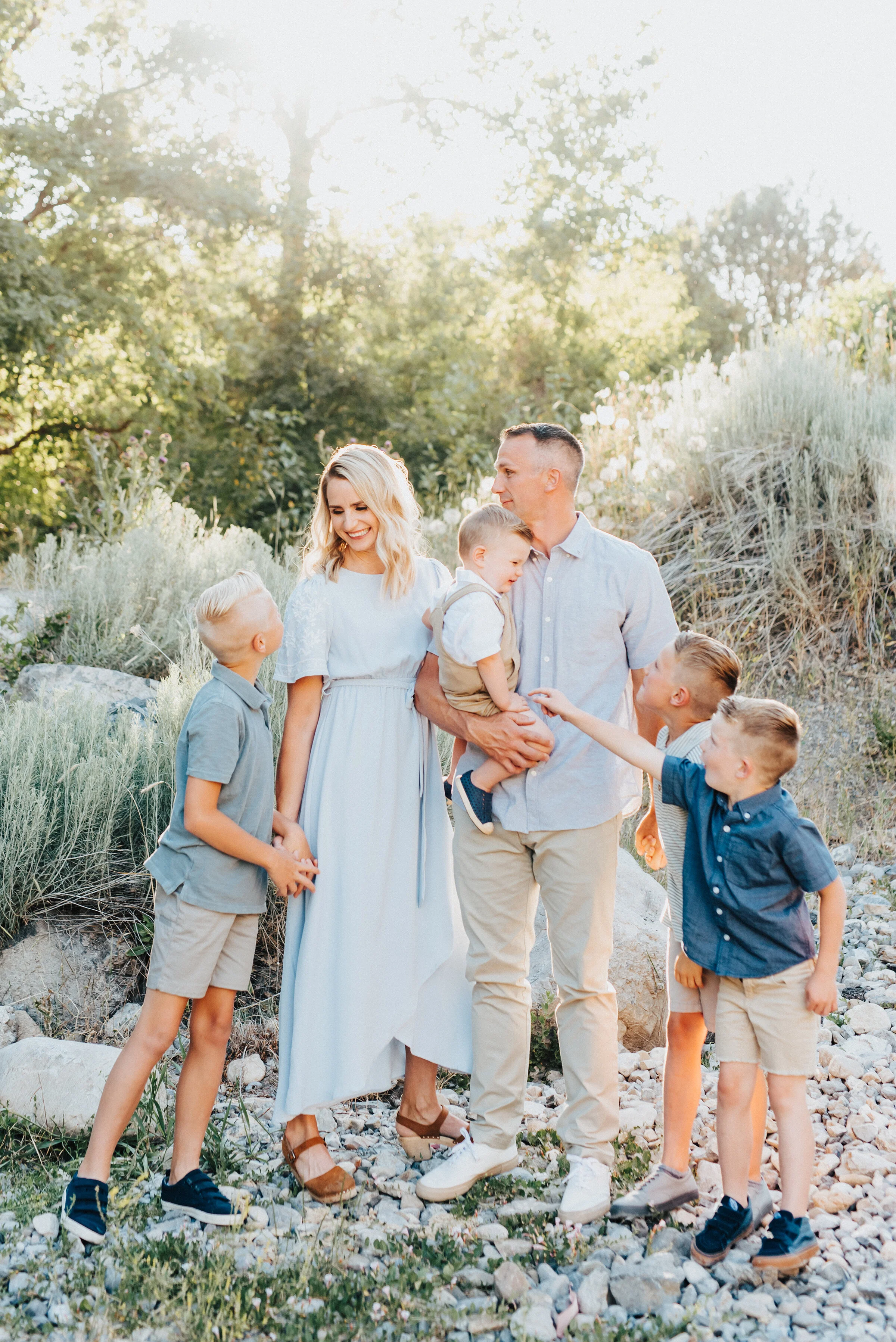  Beautiful outdoor photoshoot featuring a color-coordinating family with each of its members looking off into varying directions in Providence Canyon, UT. Light blue and khakis soft outdoor setting family photoshoot family holding hands bottom of a s
