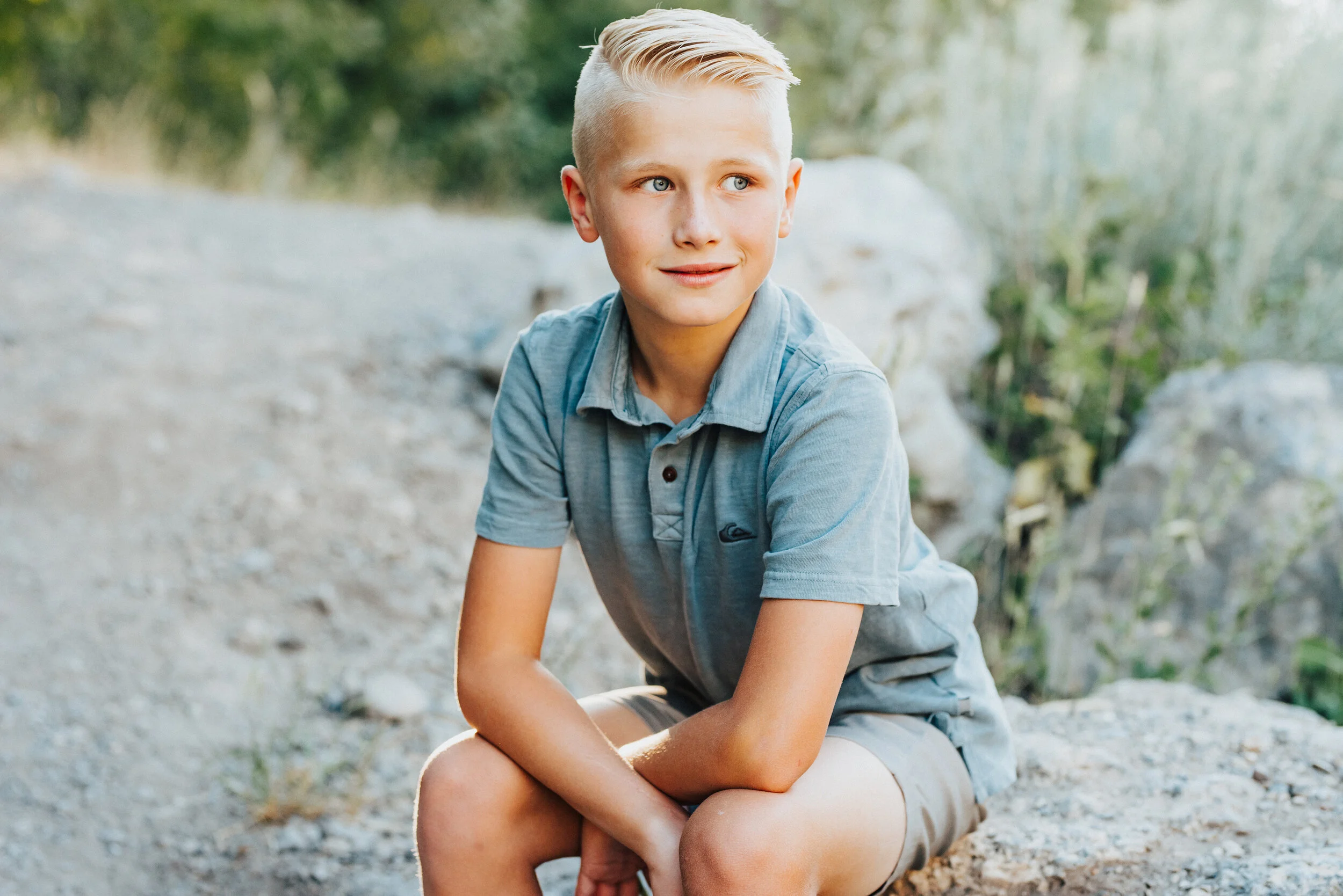 A handsome blue-eyed boy looks off into the distance while sitting casually on a rock in Providence Canyon, UT. Soft outdoor setting casual sitting blonde hair and blue eyes crossed arms sitting&nbsp; #providencecanyon #utahphotography #utah #family…