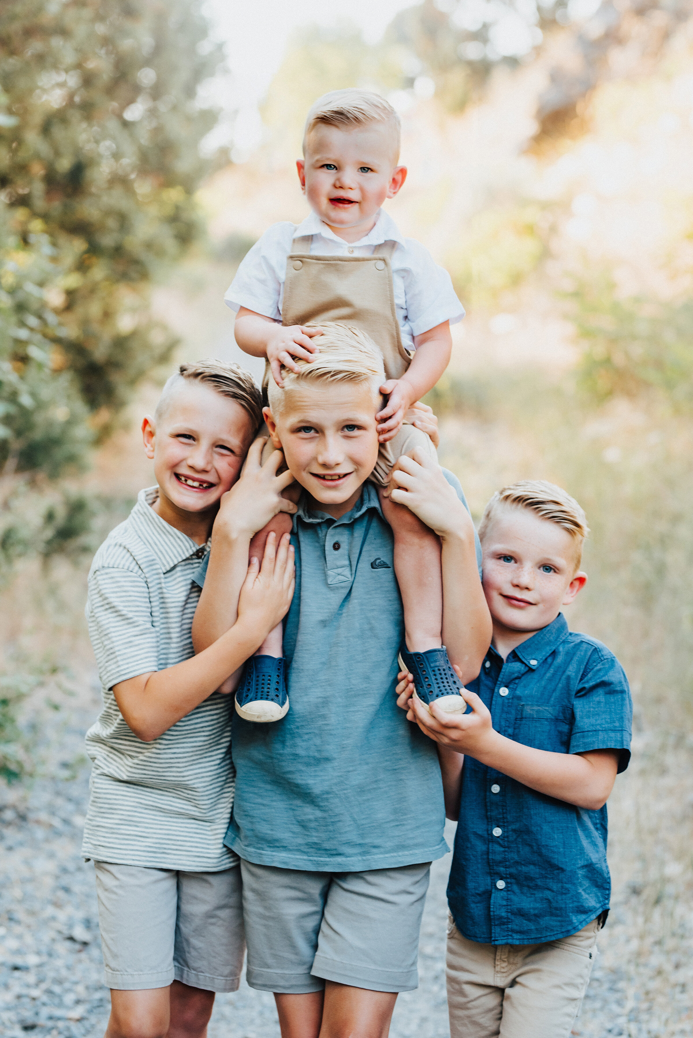  The four young boys subtly smile into the camera while the youngest rests on his biggest brother’s shoulders. Providence canyon utah light blue and khakis hugging brothers #providencecanyon #utahphotography #utah #familyphoto #family #familyphotogra