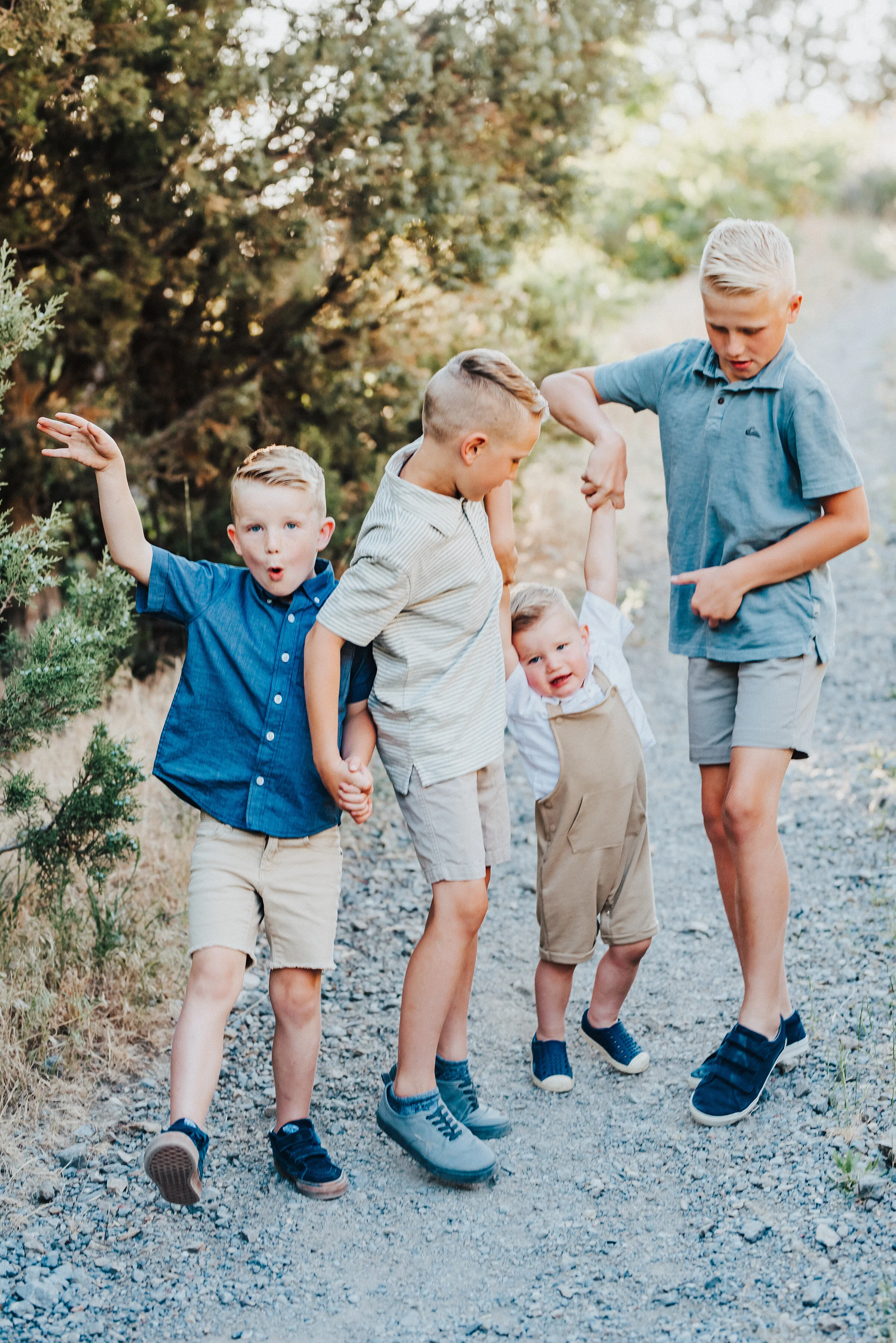  The young brothers all strike various poses while on a trodden path in the canyon. Light blue and khakis soft outdoor setting two boys life youngest boy silly faces #providencecanyon #utahphotography #utah #familyphoto #family #familyphotography #fa