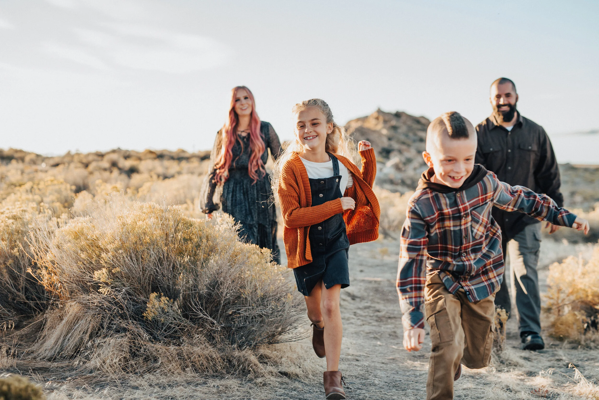Fun family pictures where daughter and son run away from mother and father in a family photo shoot by Kristi Alyse Photography. Outdoor family photo shoot in Antelope Island Utah family client attire inspiration ideas and goals fall family photo sho…