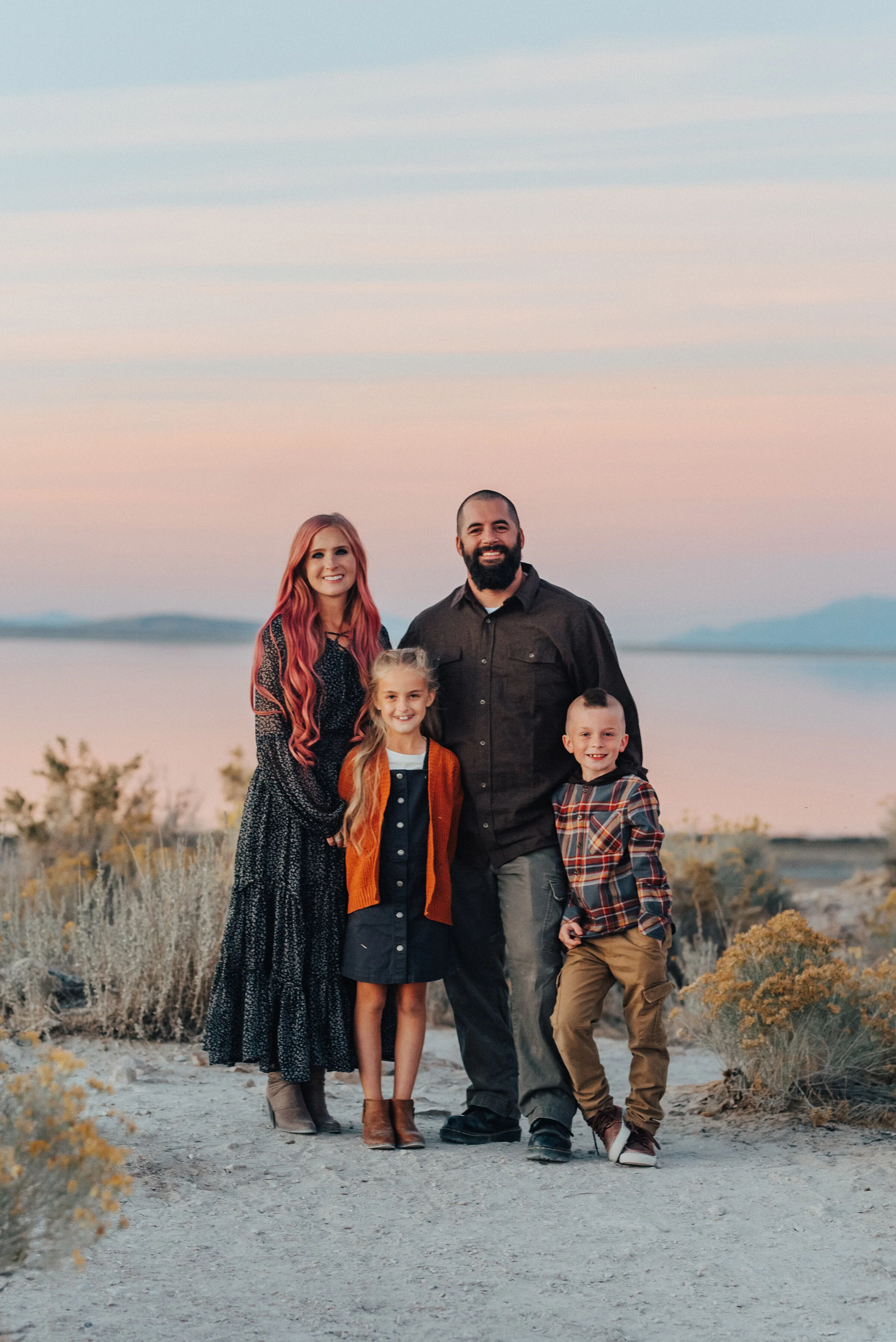  A beautiful family standing on Antelope Island beach at sun set in a professional photo shoot by Kristi Alyse Photography. Family goals fall client attire inspiration family pose inspiration ideas and goals unique family photo shoot pink hair and a 