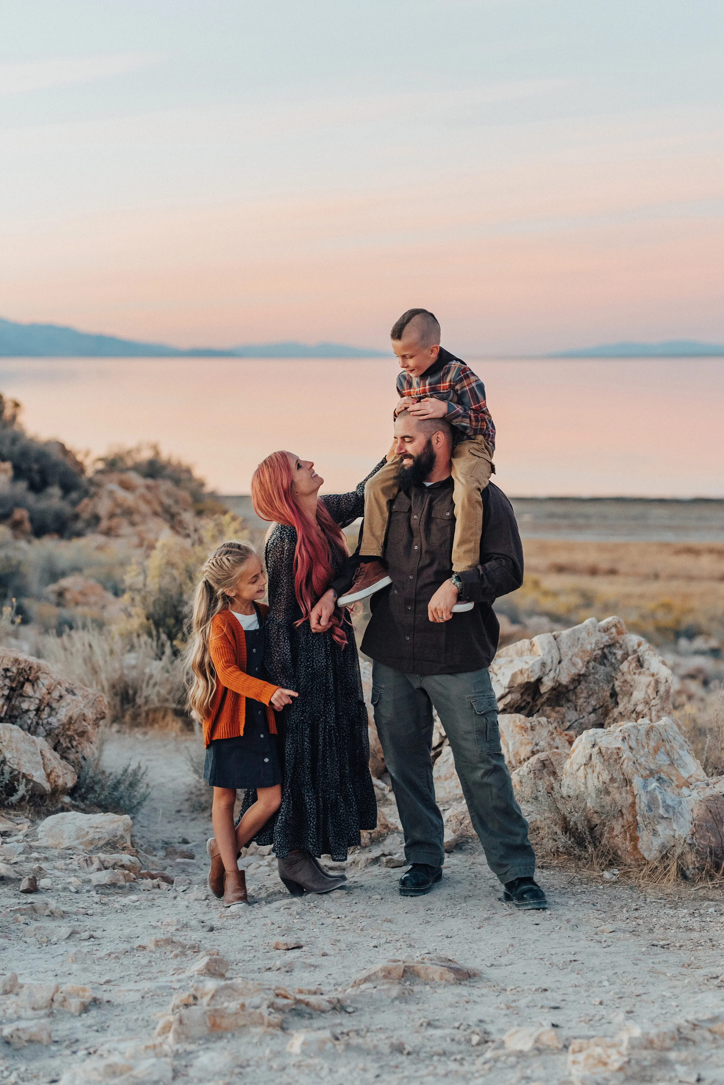  A mother and daughter look up at father and son in a beautiful warm fall family photo shoot by professional photographer Kristi Alyse Photography. Sunset goals family pose inspiration fun and playful family photo shoot SLC photographer Antelope Isla