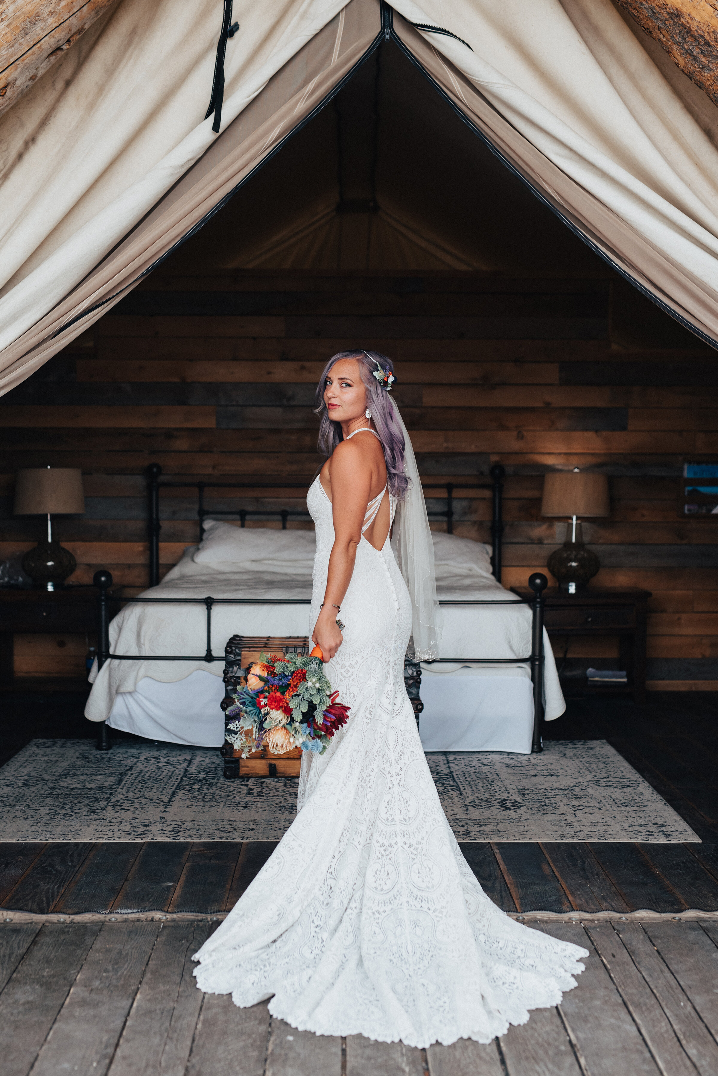  Beautiful bride with long lace backless dress and purple and orange bouquet with wood accent wall and tented bed in this bohemian styled shoot in Northern Utah by Kristi Alyse Photography. Boho wedding lace white long dress open back purple and oran