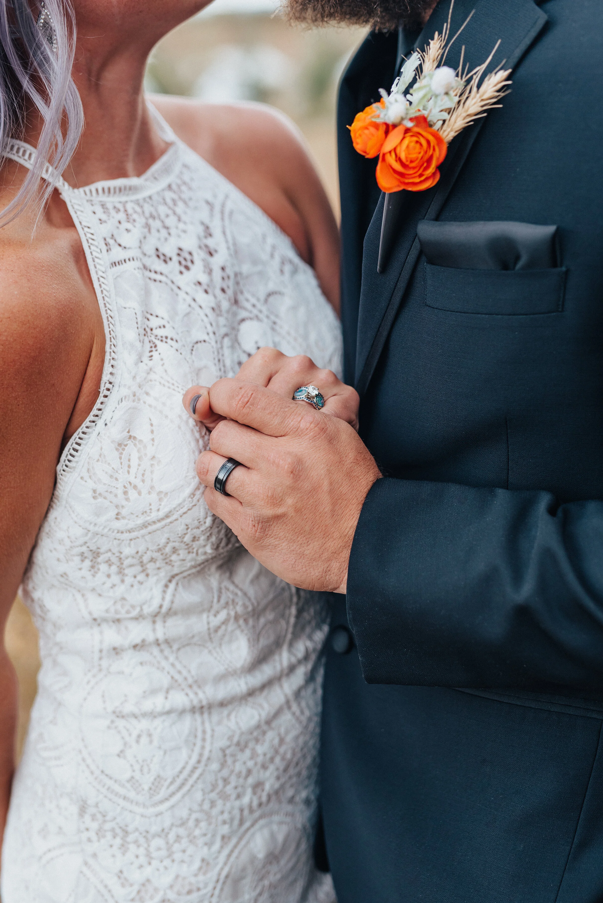  Bride and groom holding hands with wedding rings and lace high neck dress and black suit with orange boutineer in this fall styled wedding shoot in Logan Utah by Kristi Alyse Photography. northern utah boho wedding lace white high neck dress orange 