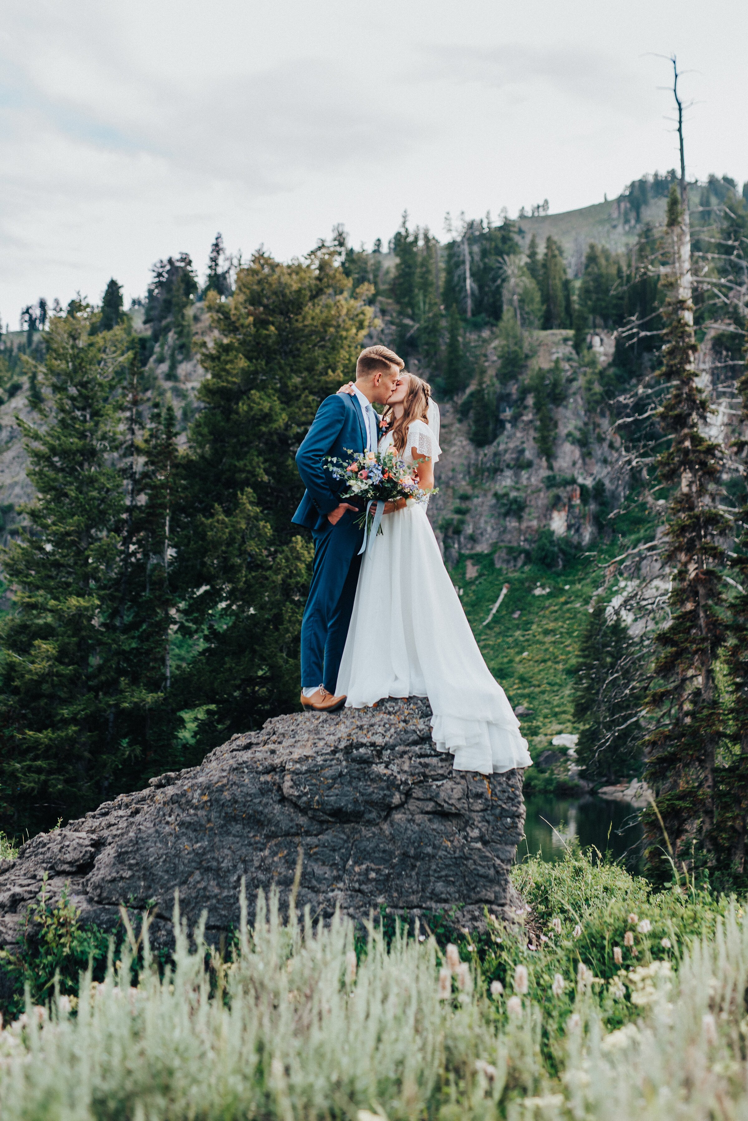  Epic mountain shot of a bride and groom kissing on a rock for summer formal photography session. Mountain wedding photography unique wedding photography northern utah photographer northern utah photography formal bridal session formal wedding photog