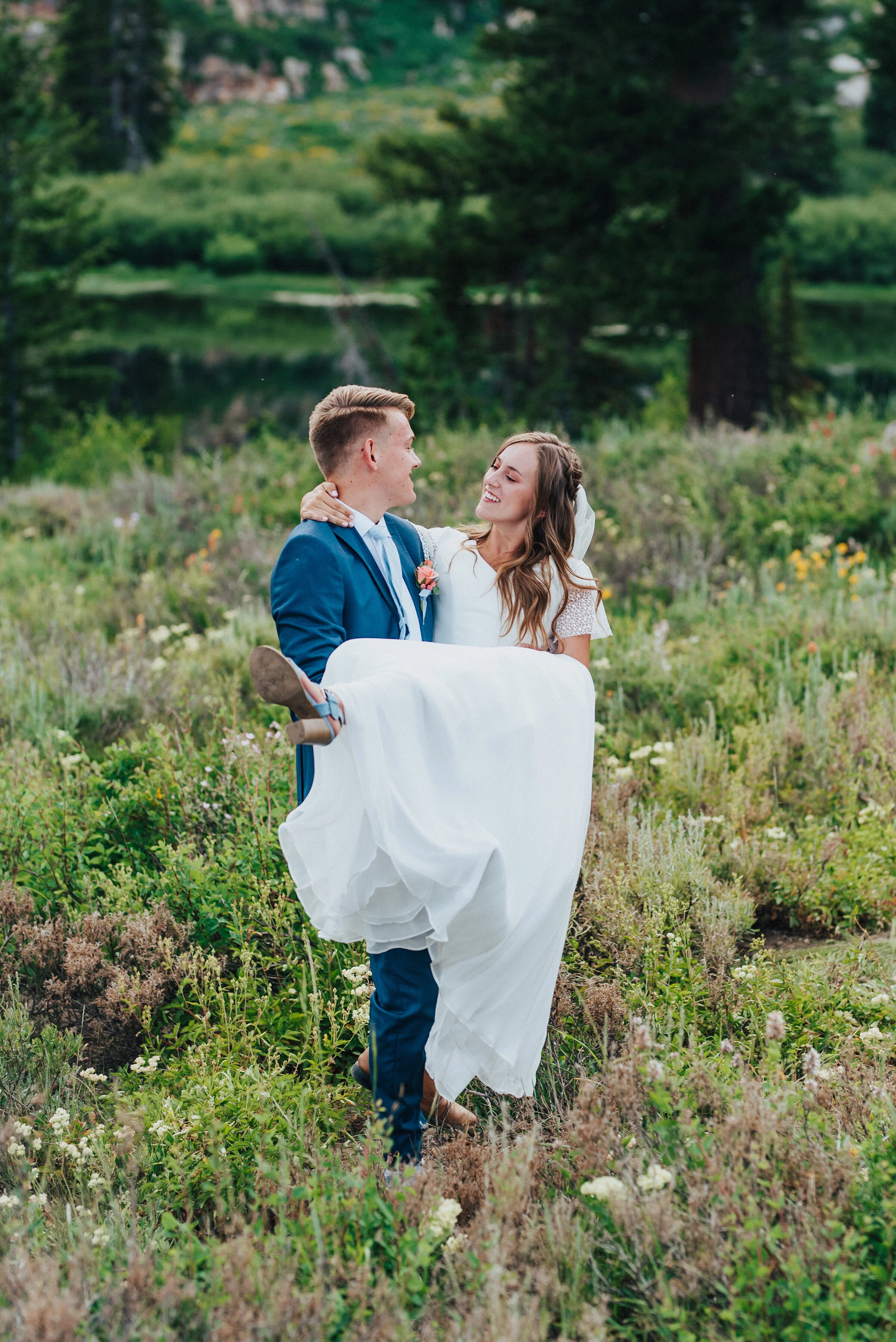  Cute bride and groom holding a wildflower bridal bouquet and touching foreheads at Tony Grove. Northern Utah wedding photography wedding formals in the mountains bride and groom wedding photography inspo unique wildflower wedding bouquet spring wedd
