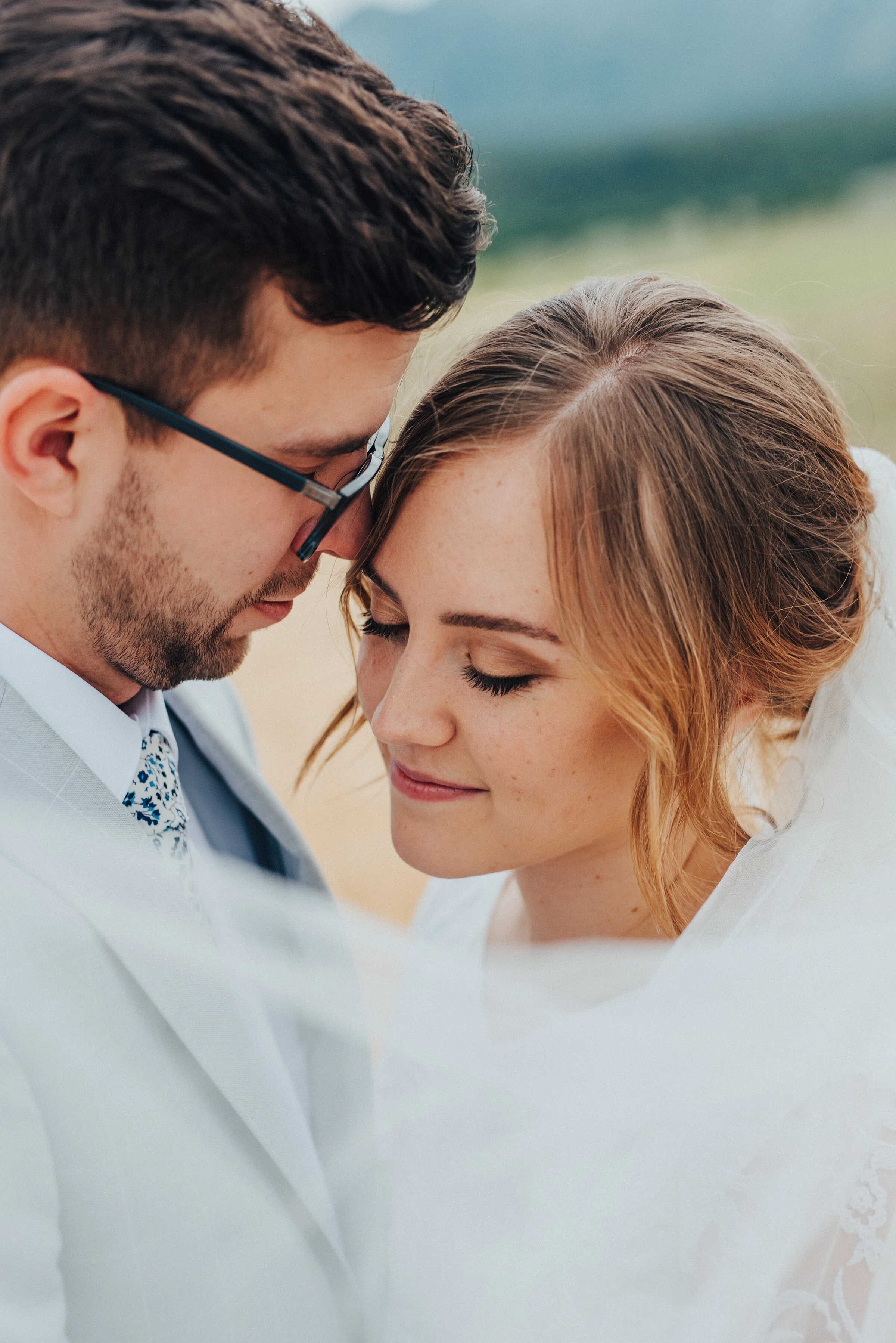  A billowing bridal veil on a stormy day made for the most romantic bridal session by Kristi Alyse Photography in Cache Valley, Utah. blowing bridal veil, modest lace sleeved wedding dress, bronze smokey bridal makeup, groom glasses, light gray groom